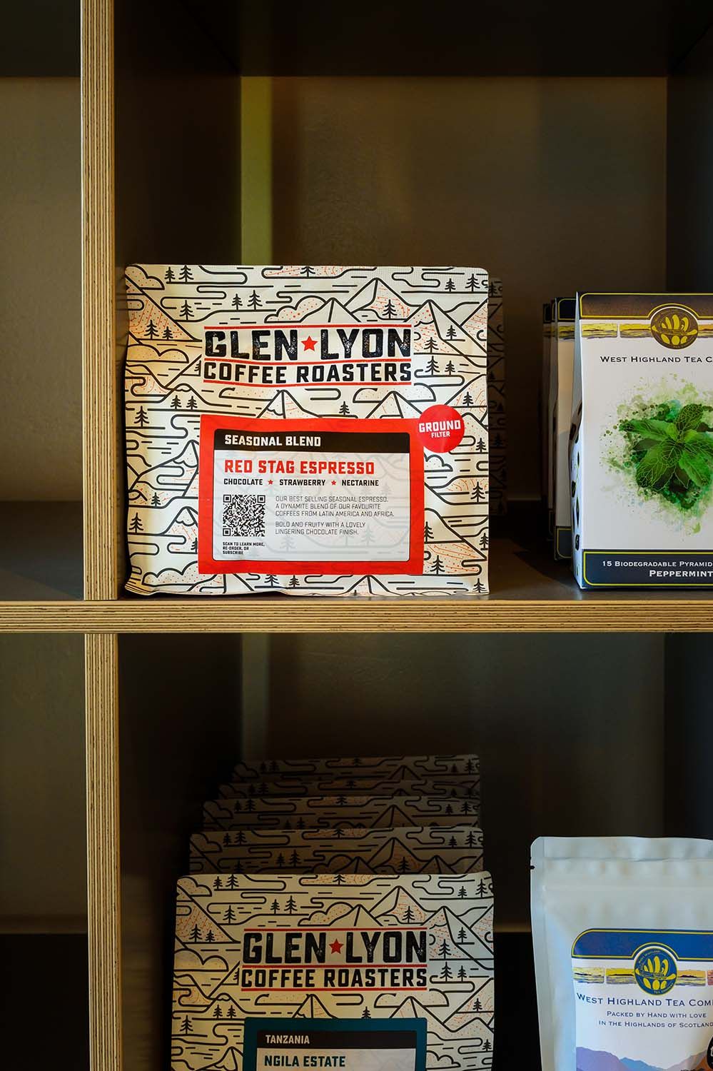 Packaged coffee beans displayed on wooden shelving for commercial product photography.