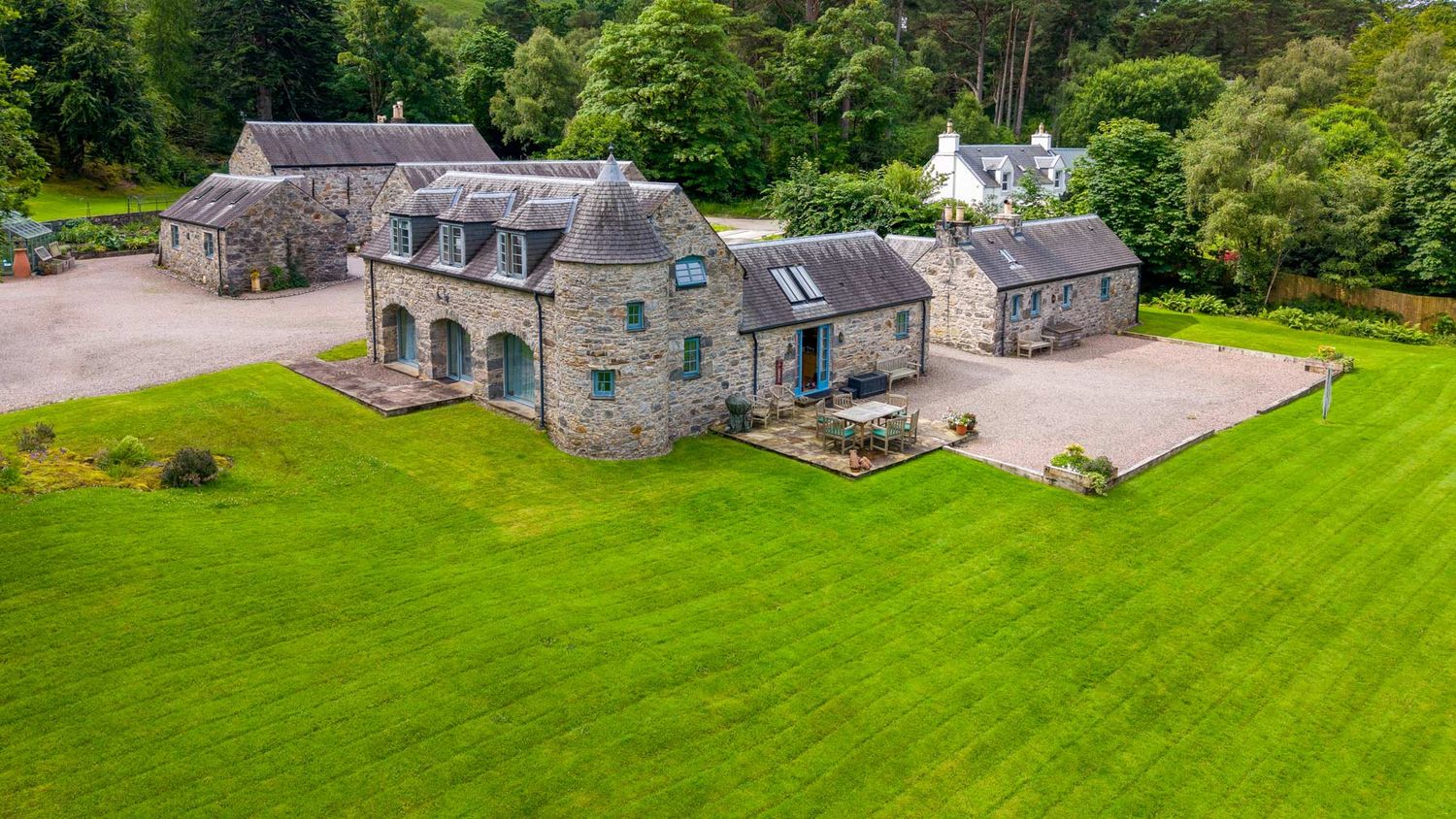 Aerial shot of a stone country estate surrounded by green fields and trees.