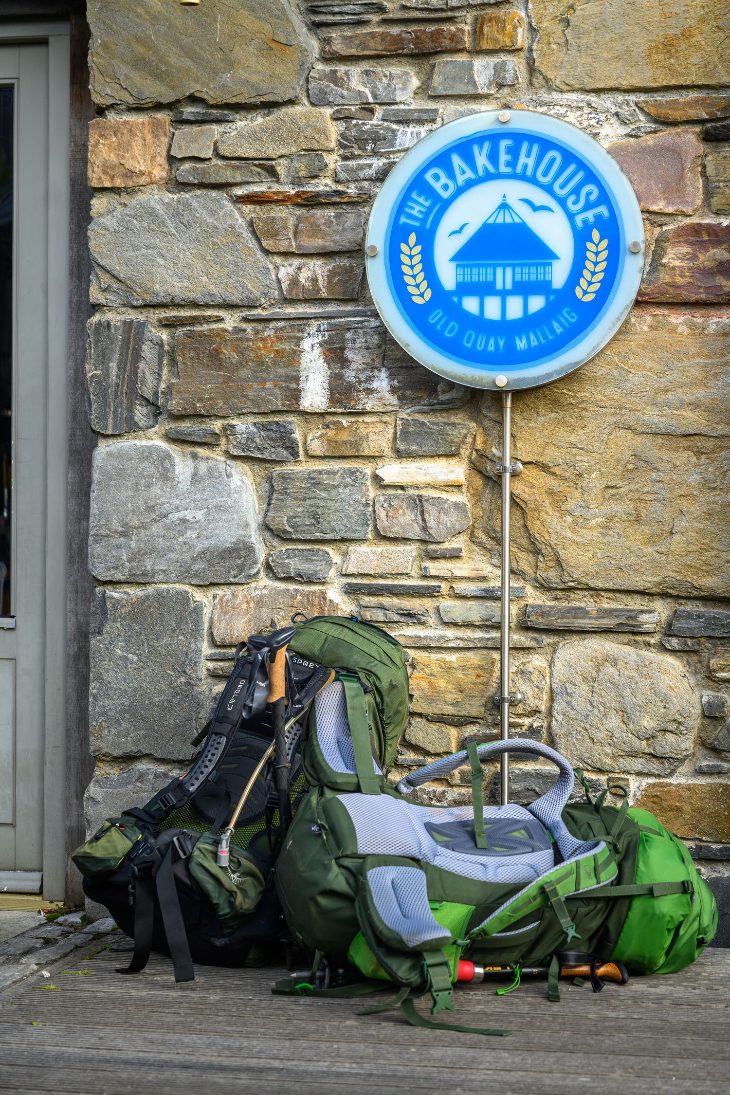 Exterior of The Bakehouse in Mallaig with its round blue sign and vintage green scooter.