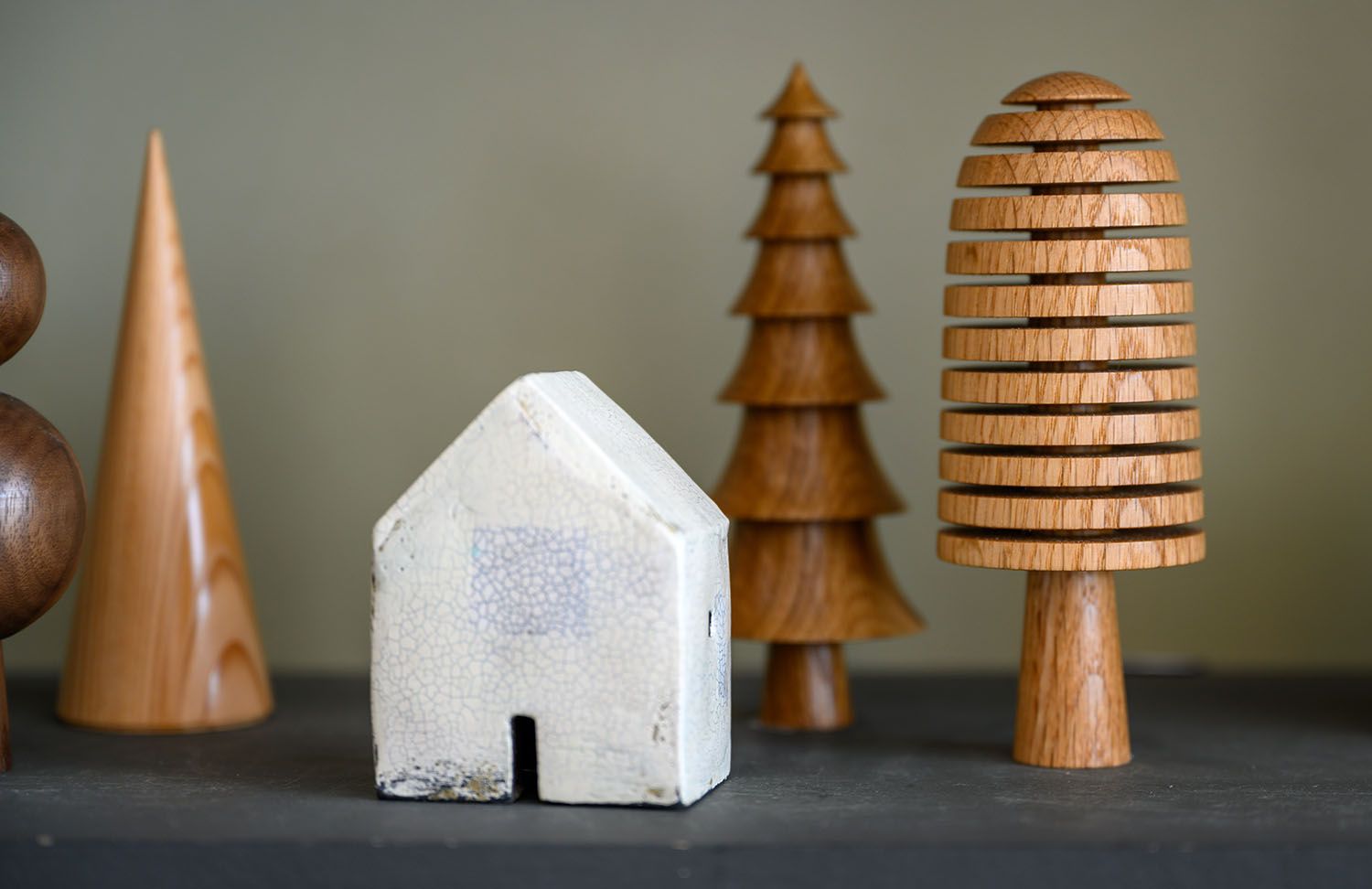 Minimalist product photography of wooden decorative trees and a white ceramic house for an independent Highland brand.