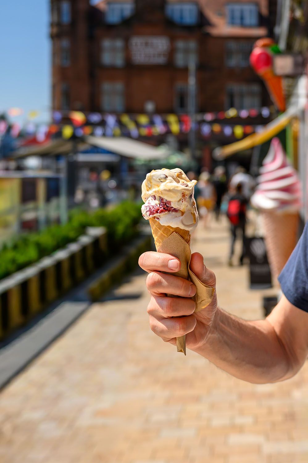 Person holding a cone of artisan ice cream outdoors on a sunny summer day in Oban.
