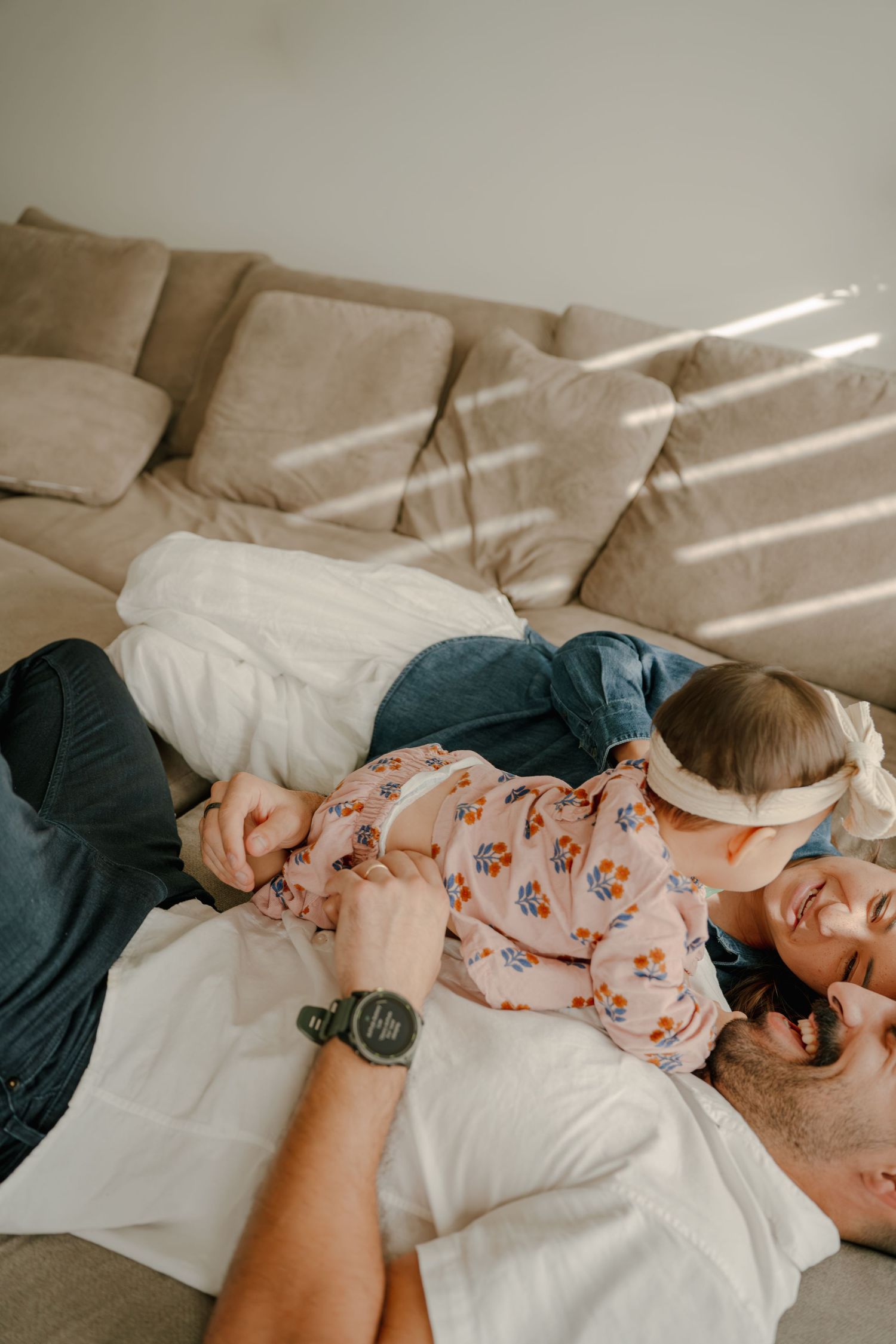 Father and young daughter laughing and cuddling together on a couch, sharing a joyful playful moment at home.