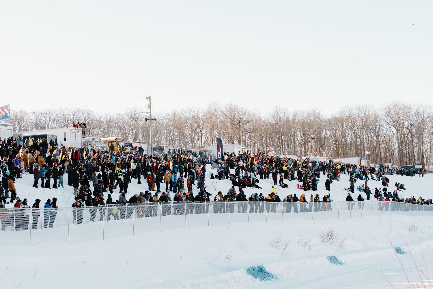Large crowd gathered outdoors at a winter snow event with bare trees.
