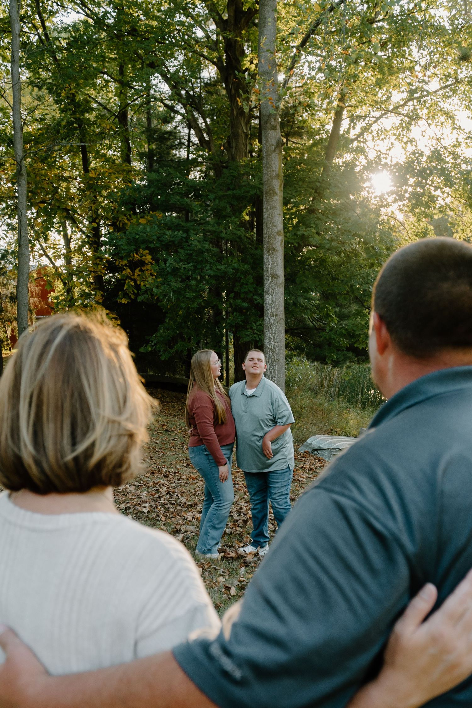 Family gathering outdoors in sunlit forest during golden hour.