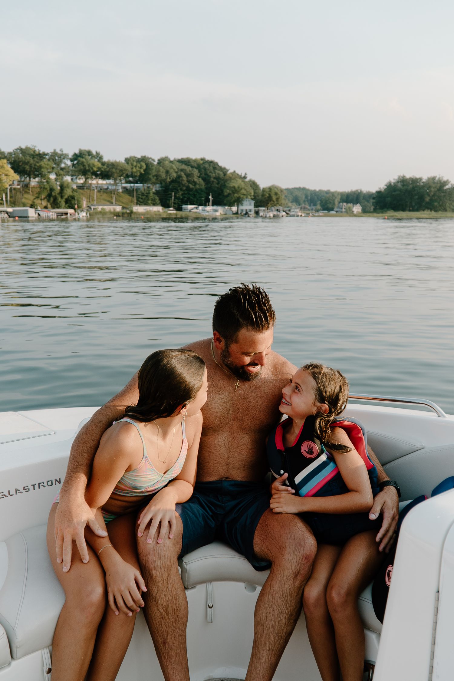 Father sharing joyful moment with two daughters on boat at lake.