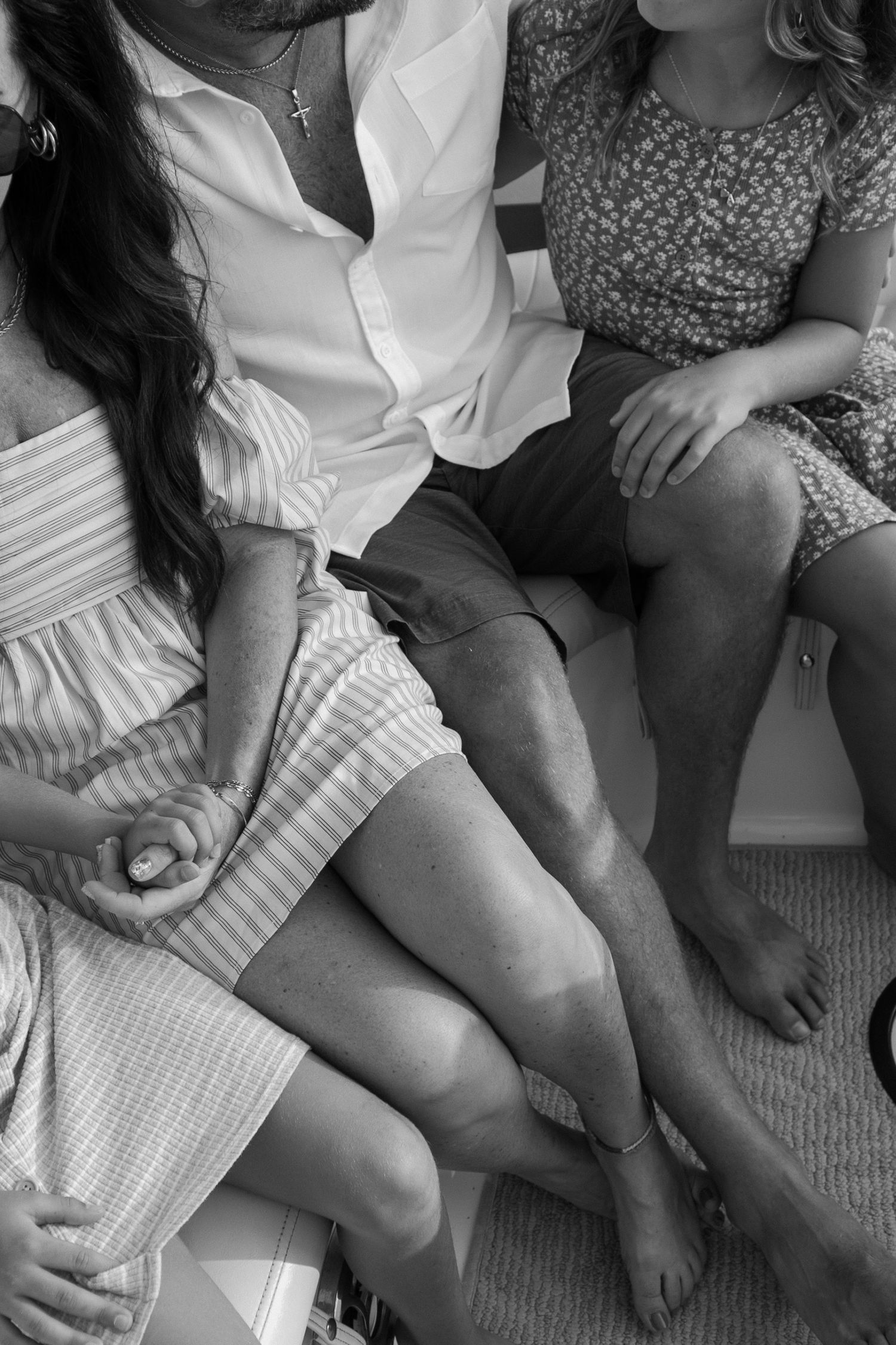 Black and white photo of three people sitting together in casual summer attire.