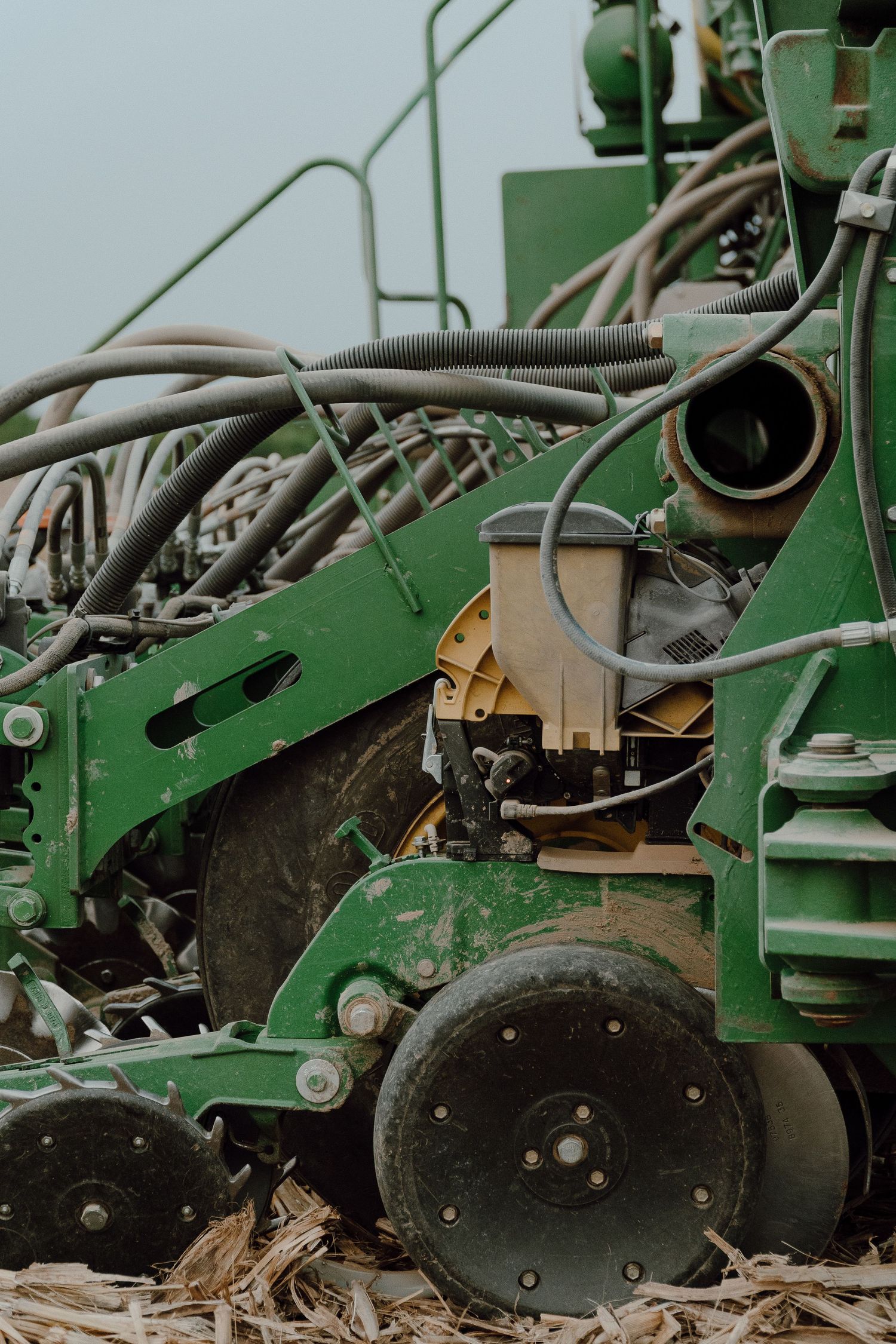 Close-up of green John Deere planter machinery with hydraulic hoses and disc openers.