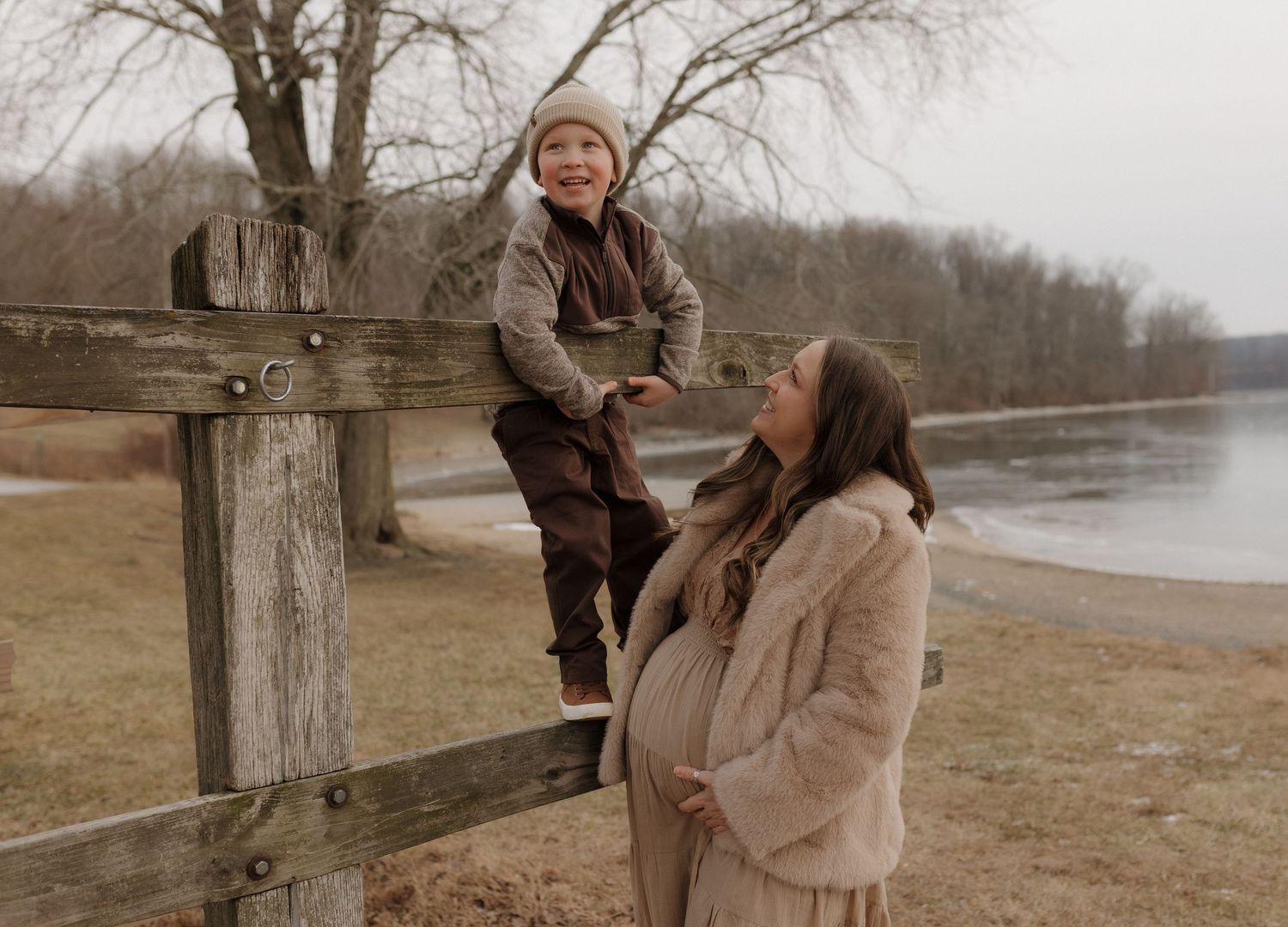 A heartwarming family moment captured on a cloudy day by a lake with bare winter trees in the background.