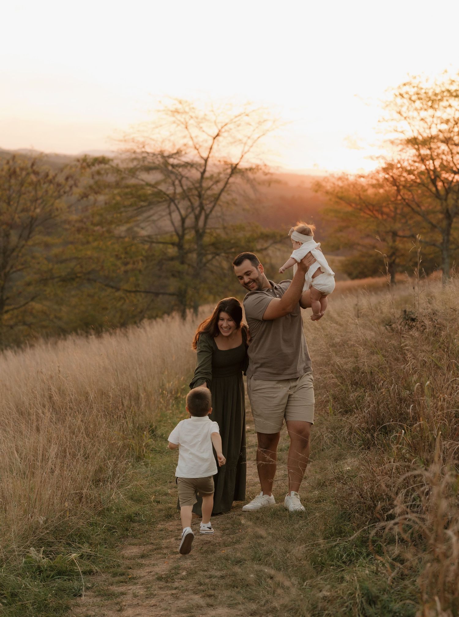 A family walking together on a hilltop path during golden hour.
