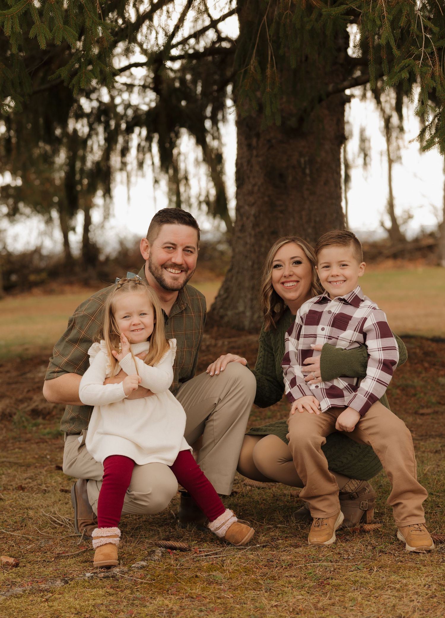 Family poses together under a large tree during an autumn outdoor photoshoot.