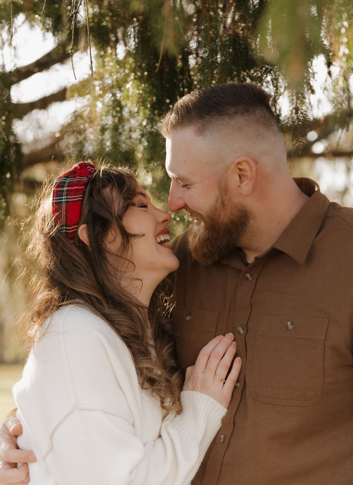 A romantic outdoor photoshoot under willow trees in warm natural lighting.
