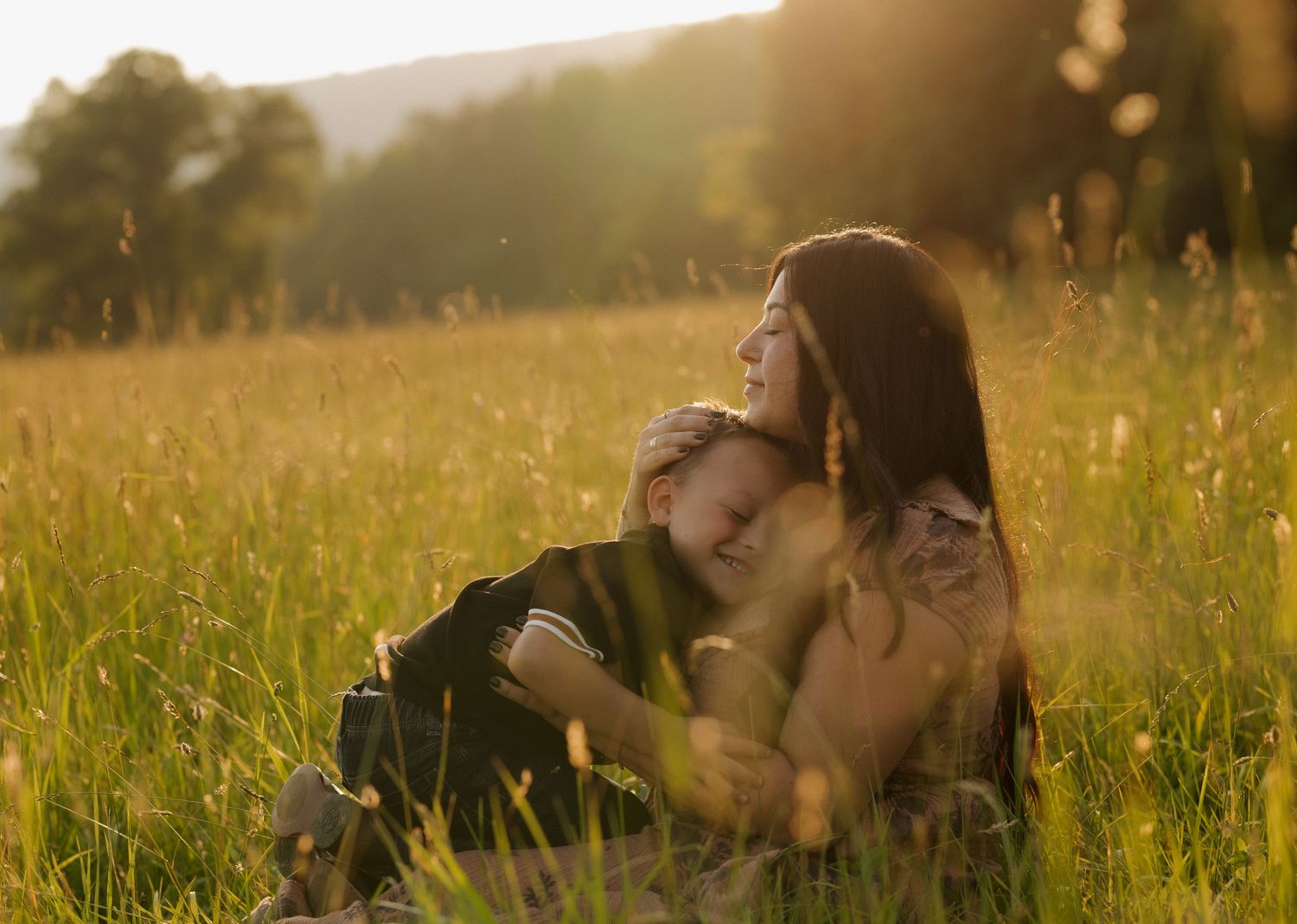 Intimate moment shared between couple lying in tall grass at sunset.
