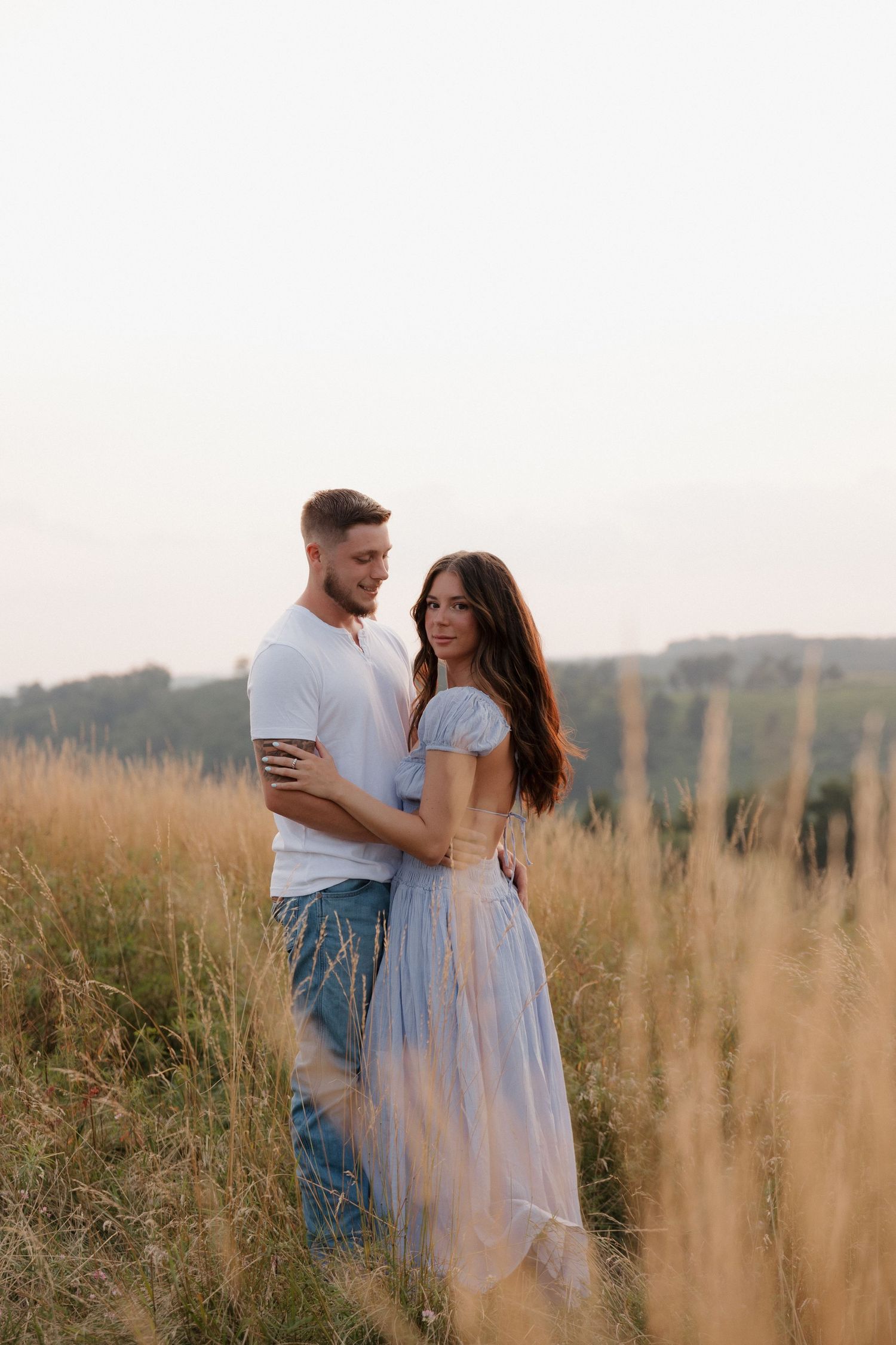Couple in casual attire sharing intimate moments in a rustic field setting.