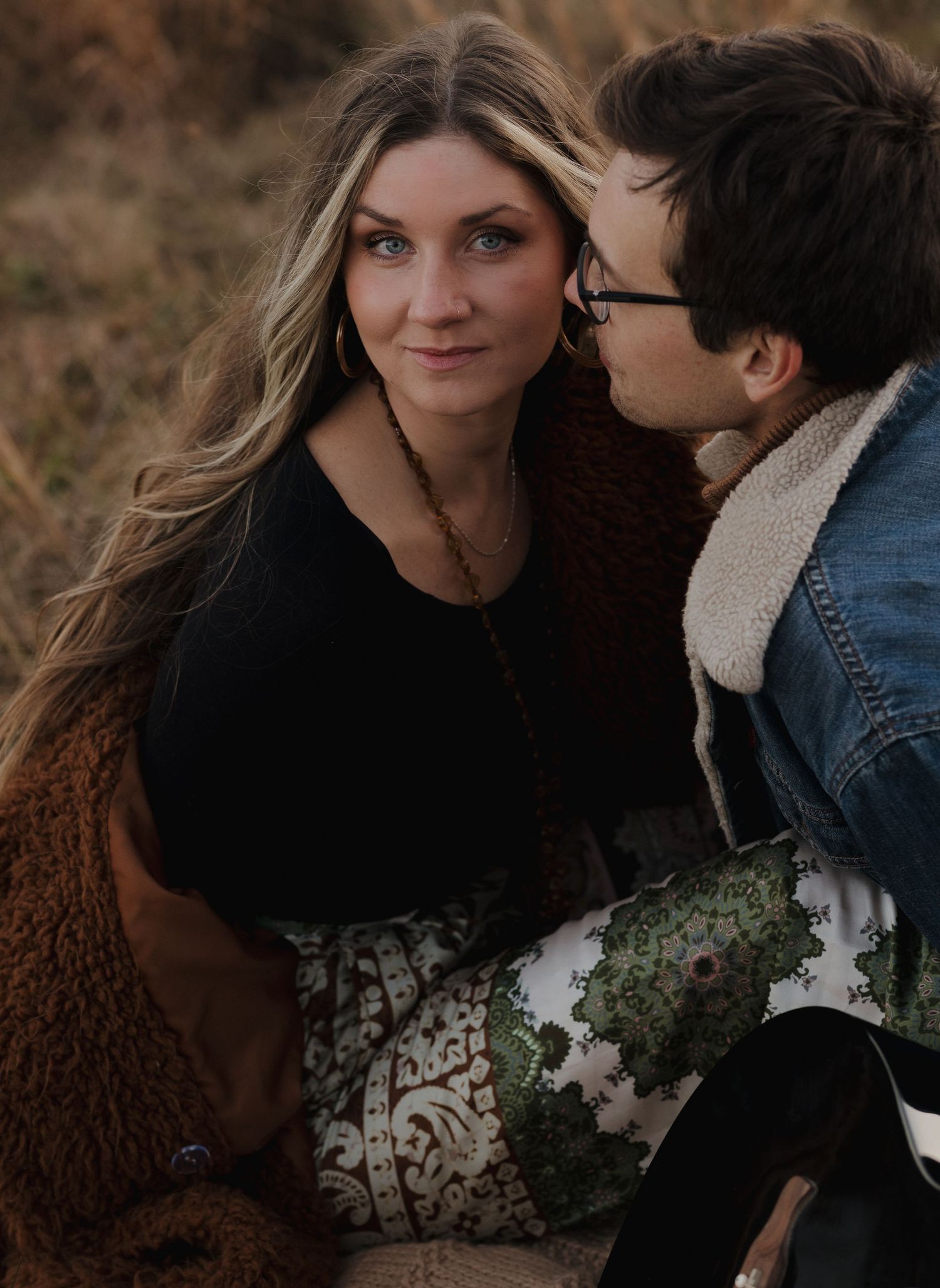 Cozy autumn couple photoshoot with rustic brown and denim outfits in natural setting.