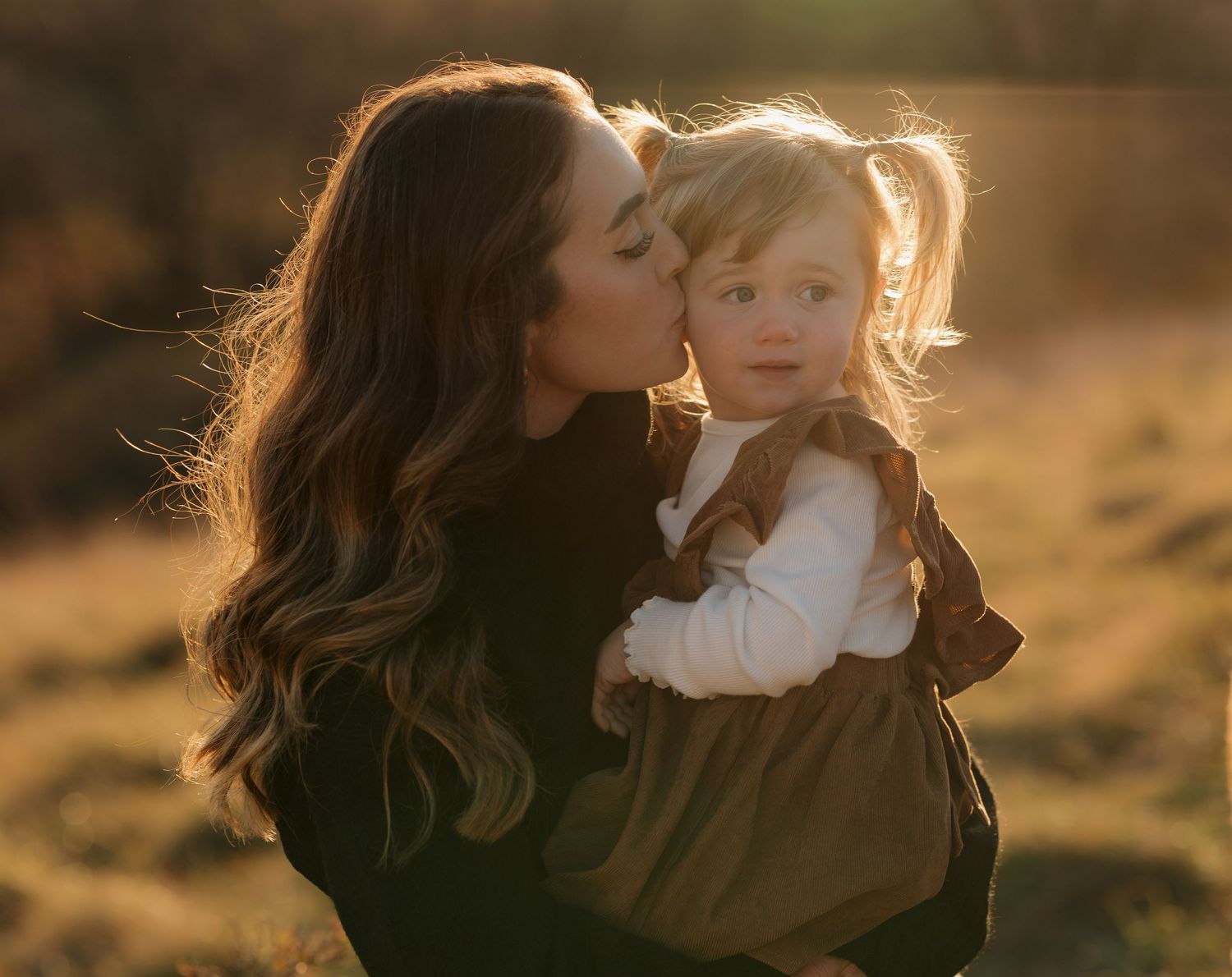 A tender family moment captured in warm sunlight during a sunset photoshoot.