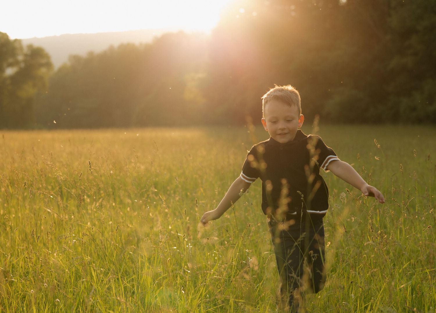 Children playing in golden meadow with mountains in background.