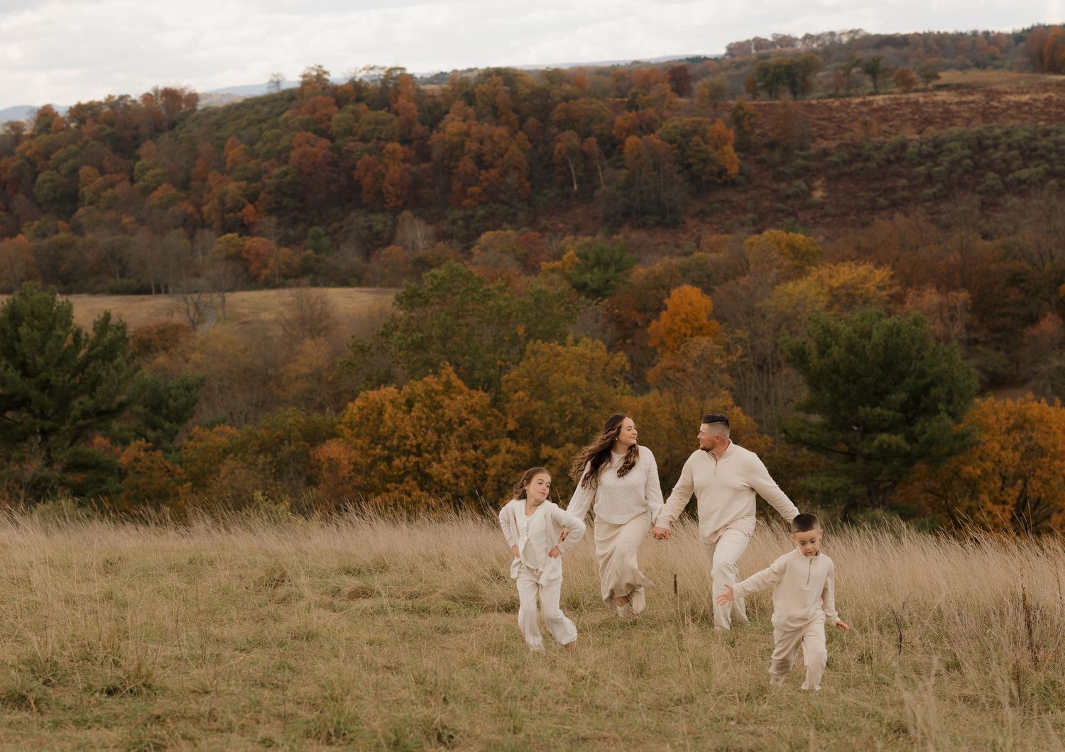 A group in white outfits walks through a golden autumn field during a fall photoshoot at sunset.