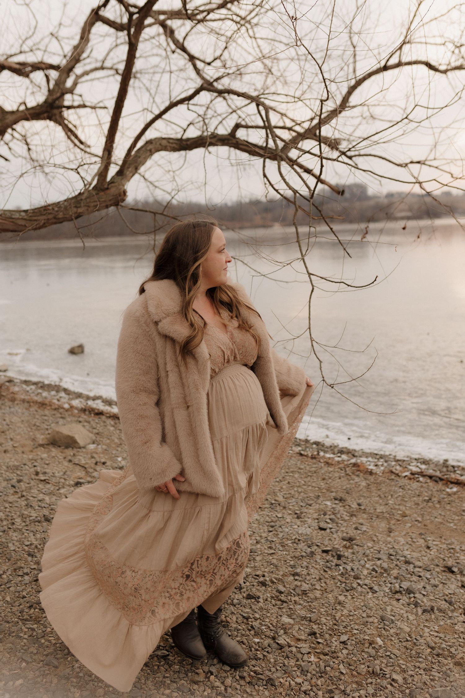 Artistic portrait series in neutral tones showing movement of flowing dress by waterfront.