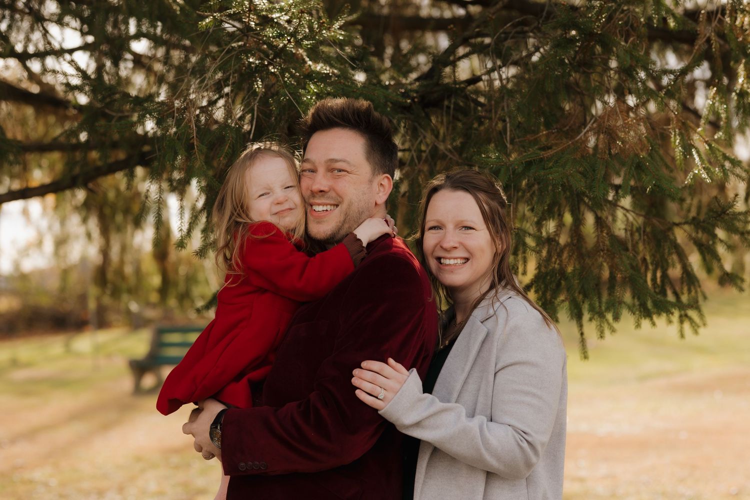 Couple embraces during outdoor winter photoshoot in red and gray attire.