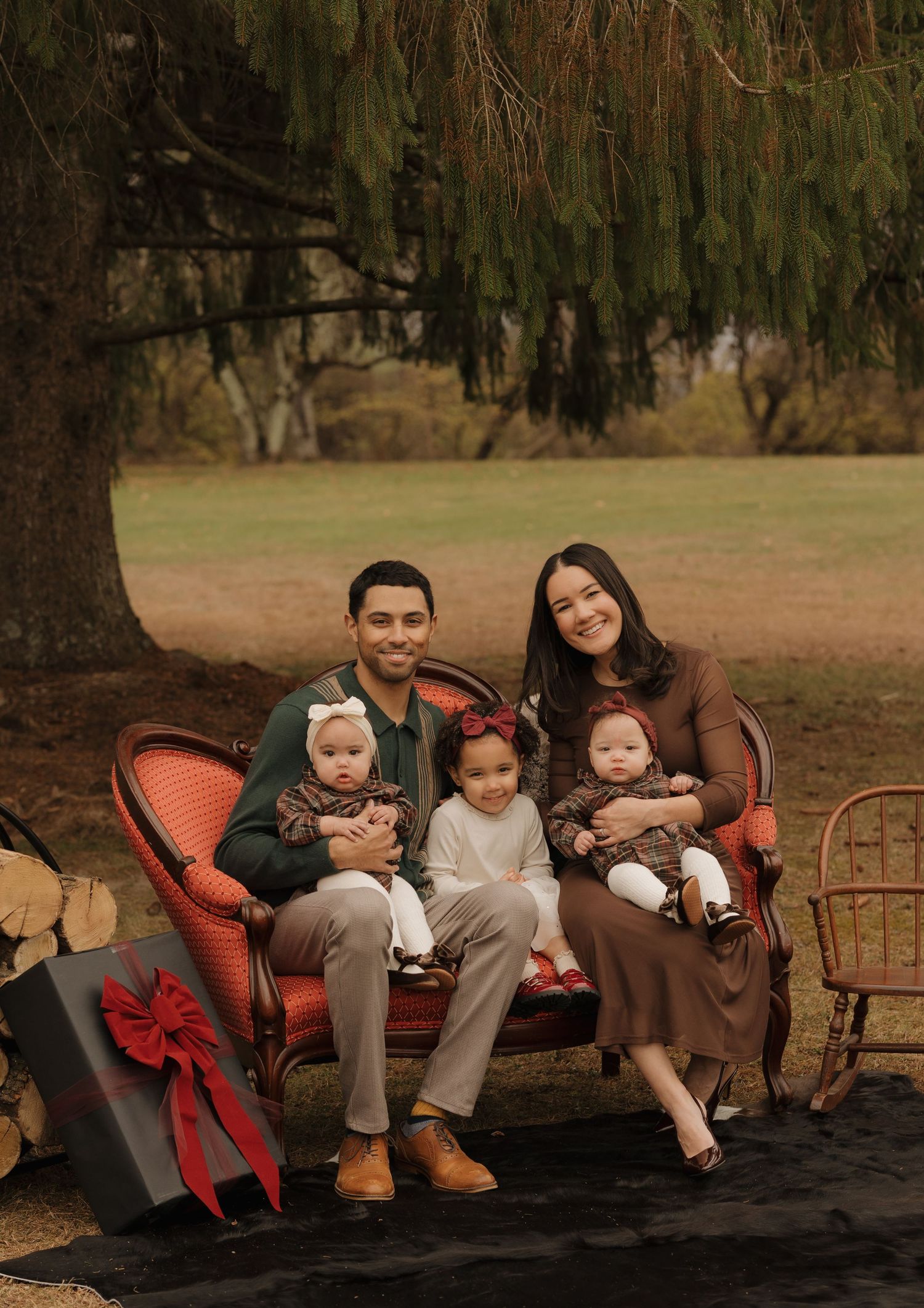 Family seated together on vintage furniture in an autumn outdoor setting.