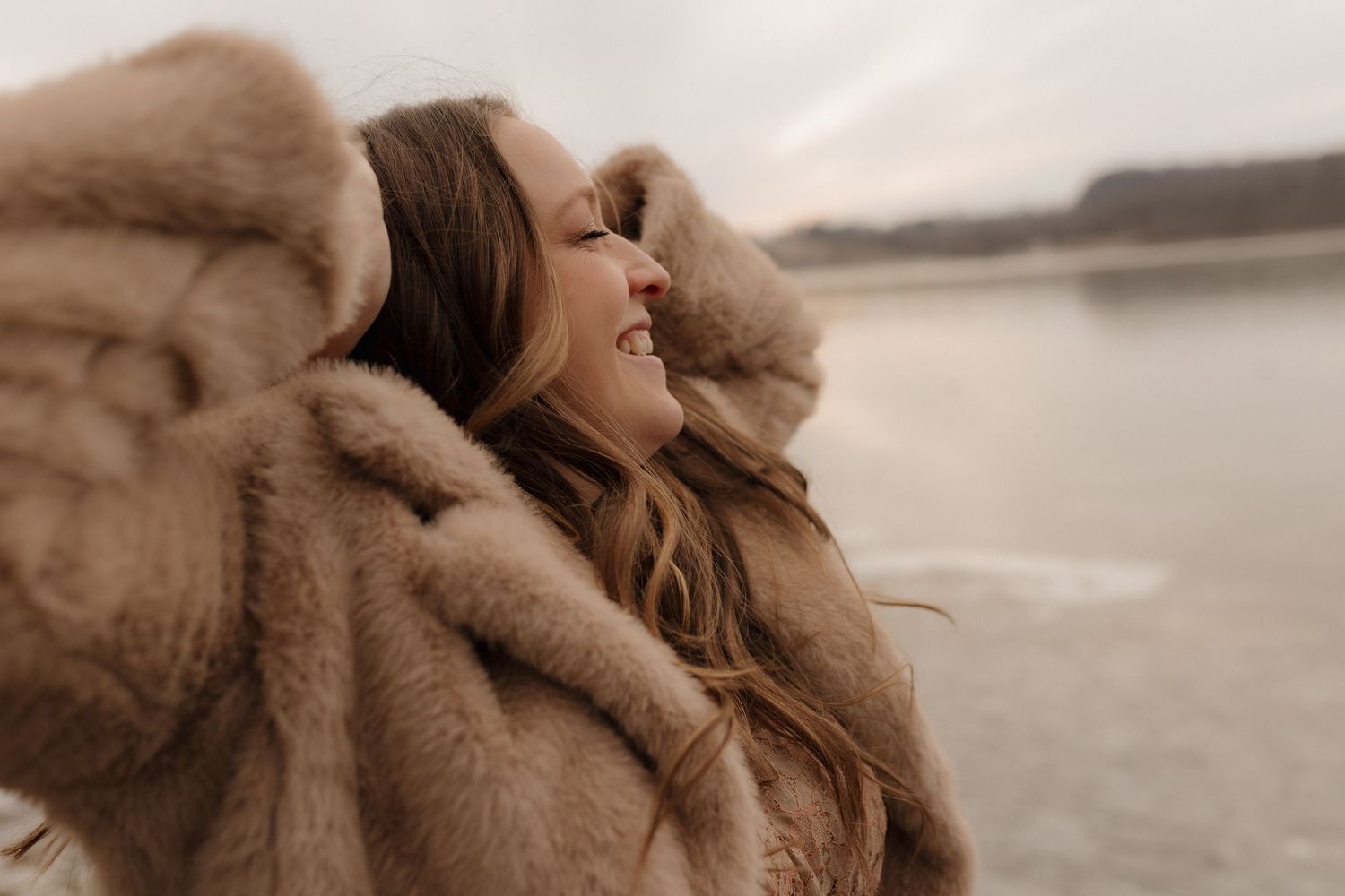 Candid close-up portrait in soft beige tones against a misty waterfront backdrop.