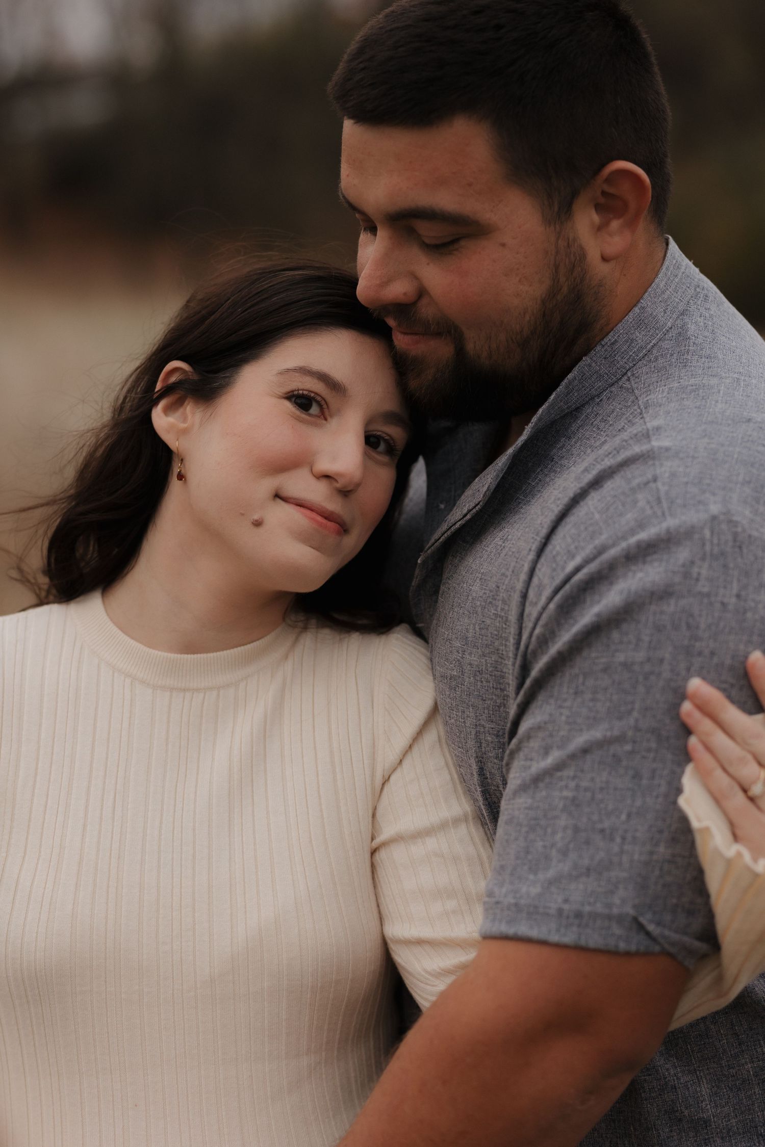 A couple shares an intimate moment while wearing casual attire outdoors.