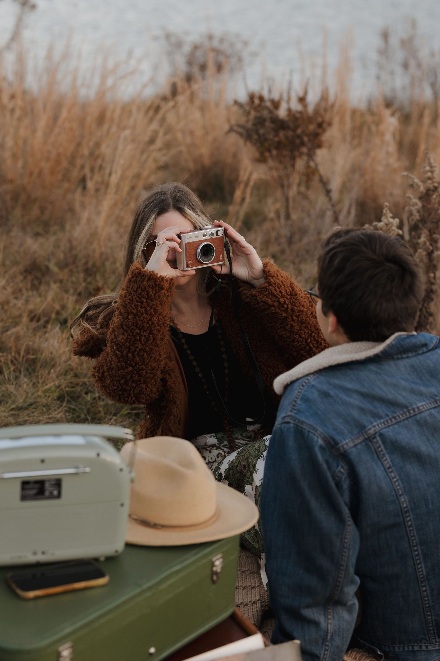 Romantic outdoor photoshoot with vintage typewriter and brown teddy coat against autumn backdrop.
