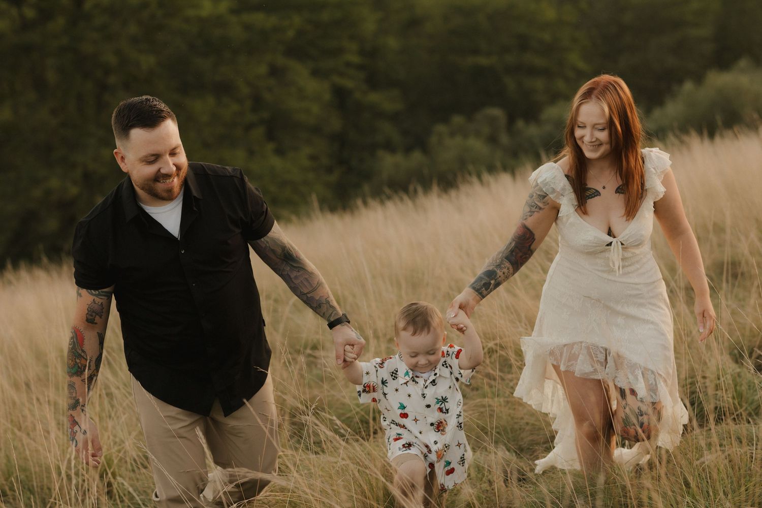 Family playing and walking together through tall grass field at sunset.