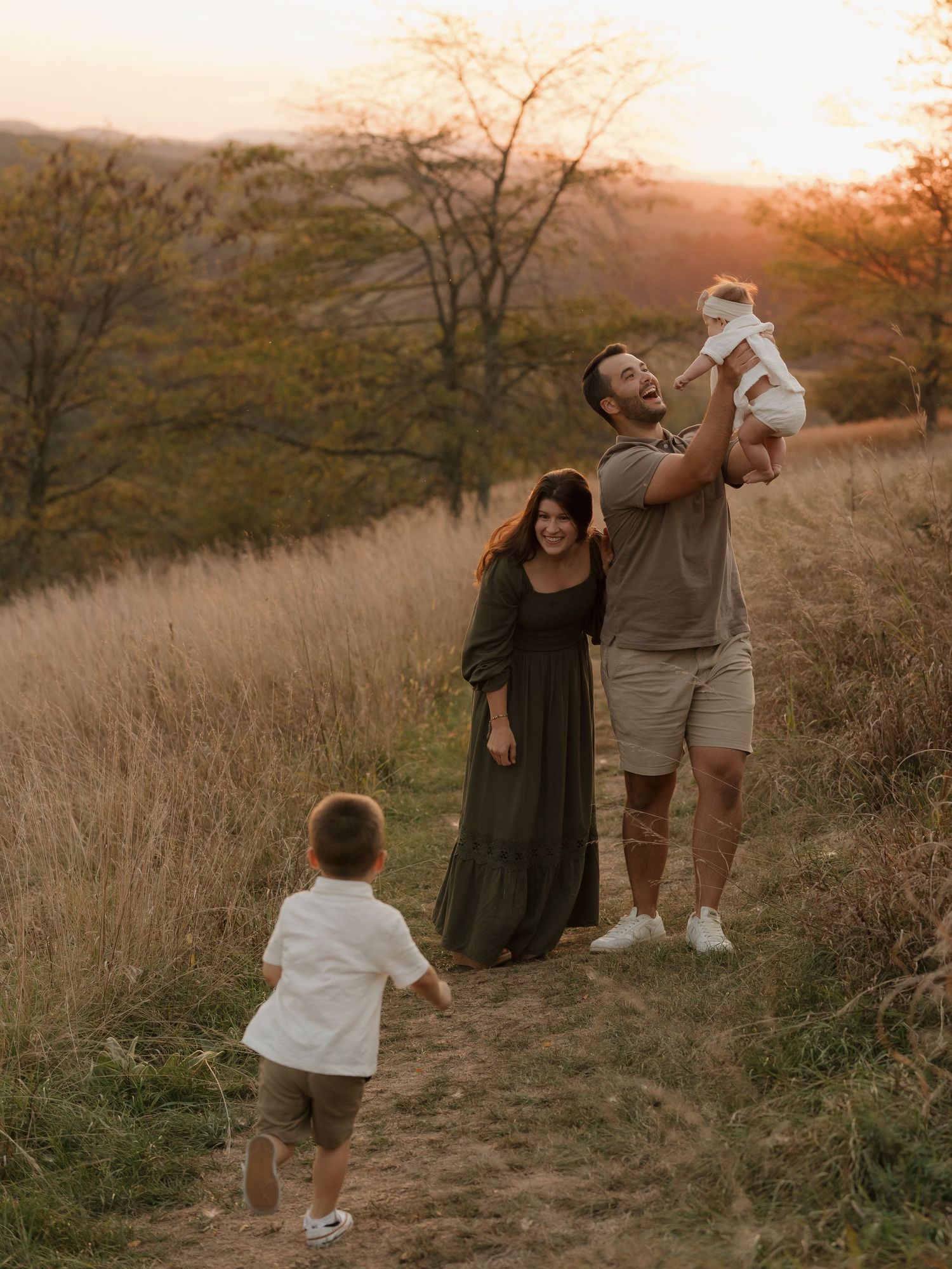 Family enjoying a tender moment together in a golden field at sunset during an outdoor photo session.