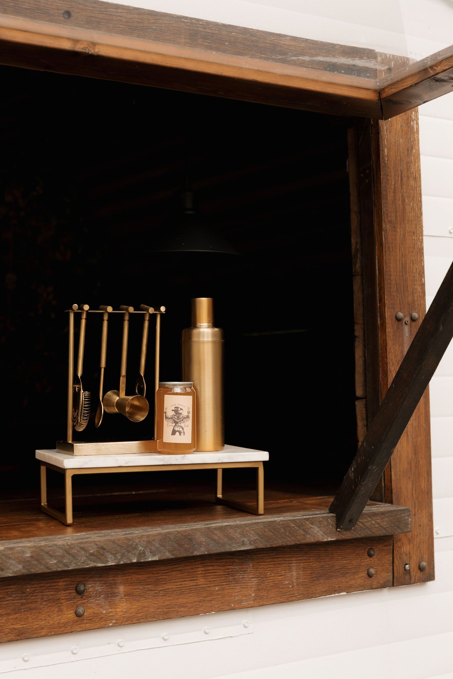 Rustic wooden window display featuring brass decor items and vintage accessories.