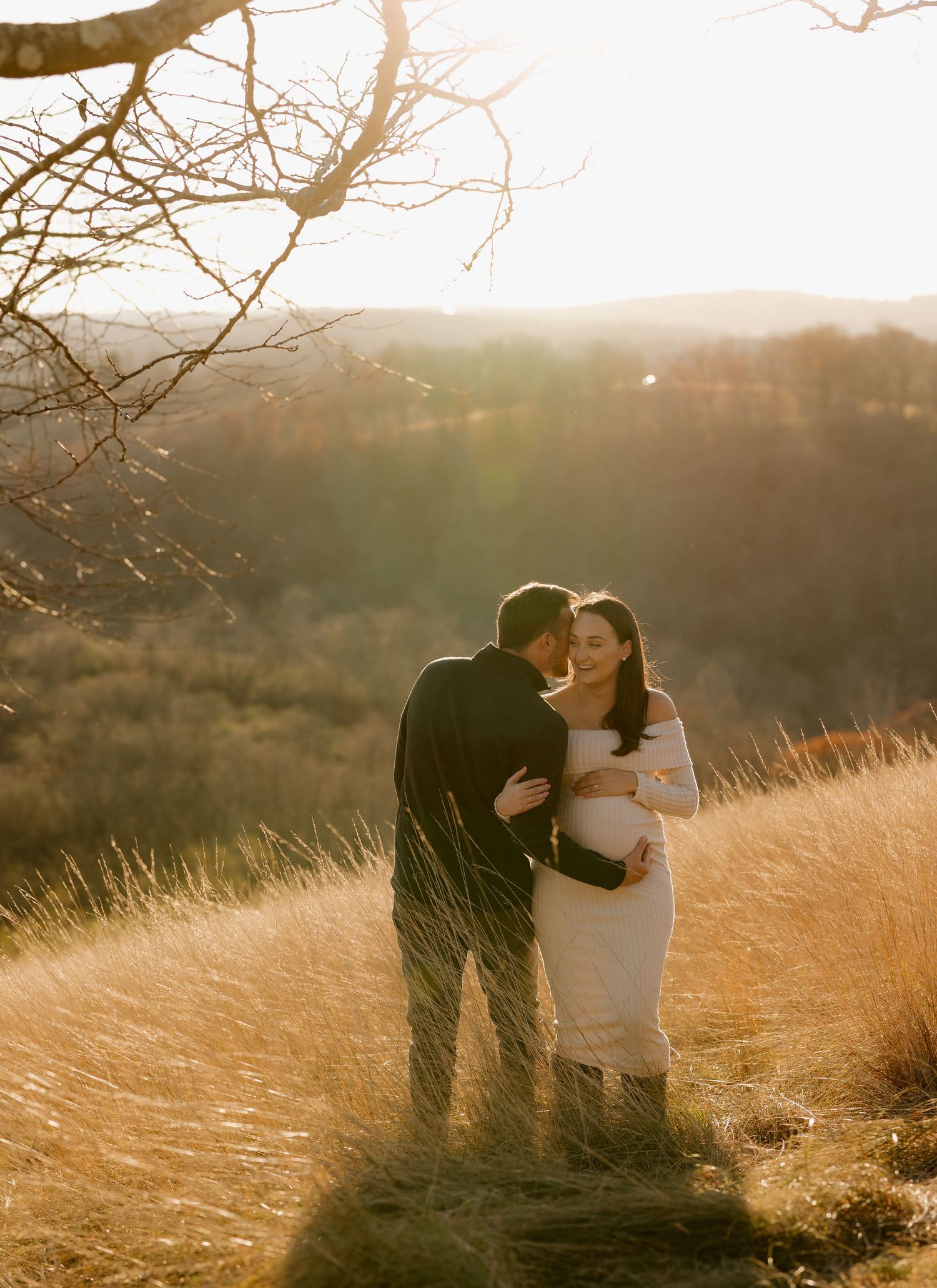 A romantic couple shares intimate moments in a golden field at sunset.