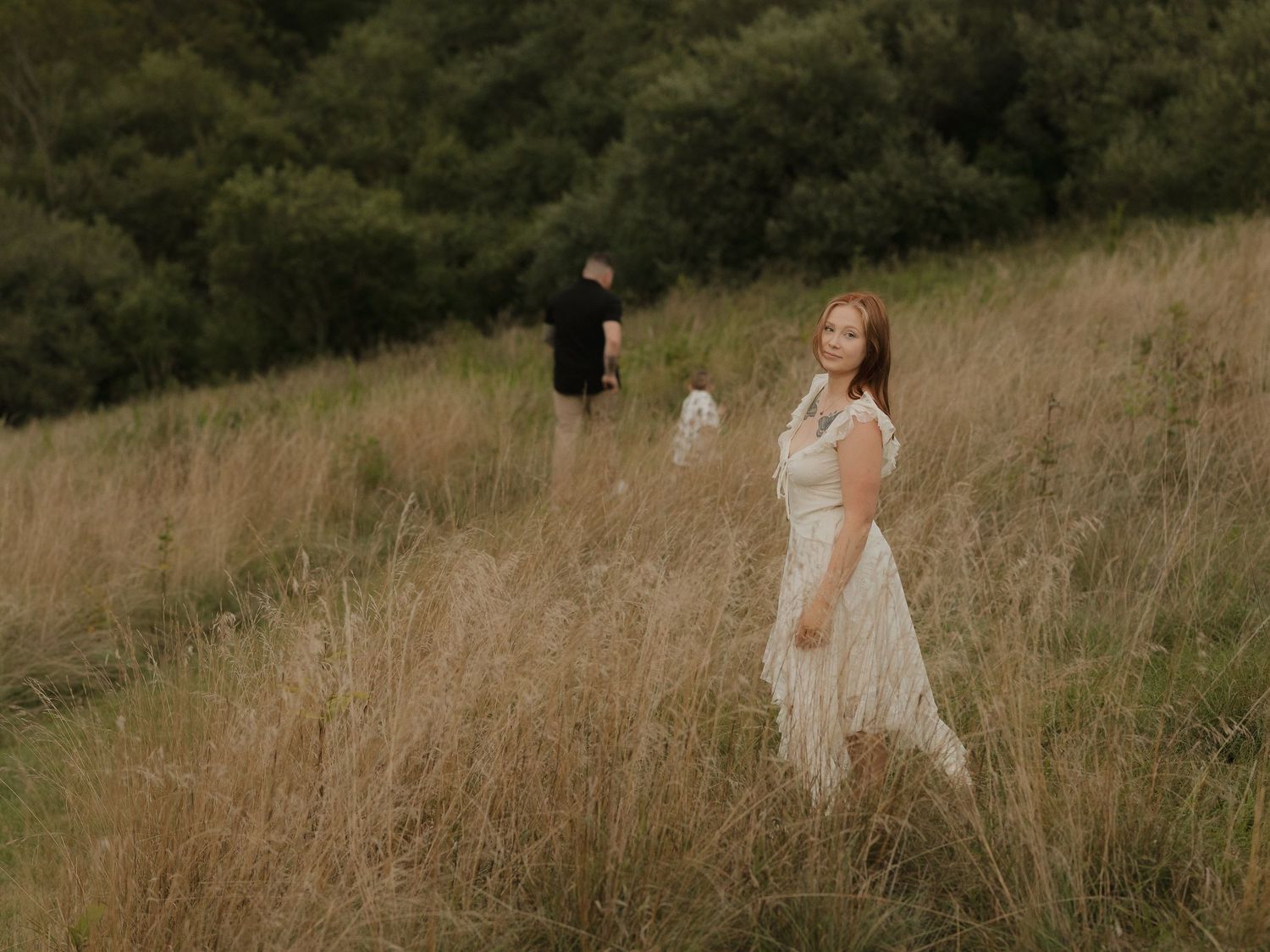 Couple walking through scenic hillside meadow during golden hour photo session.