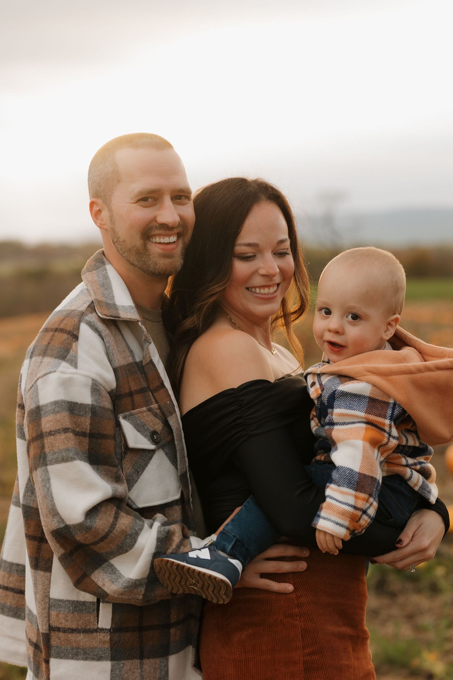 Family laughs and plays together in an autumn field.