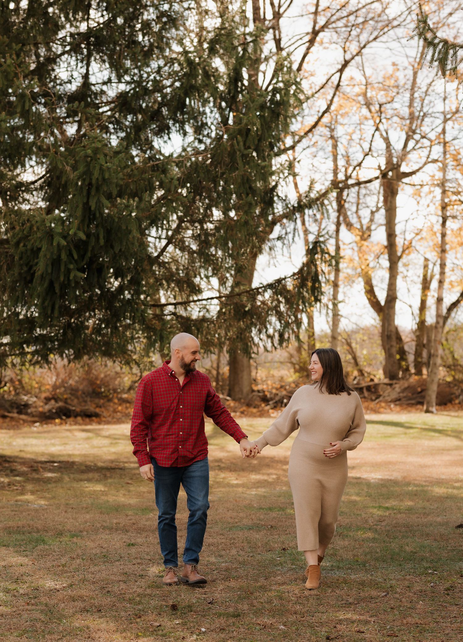 Couple walking and playing together in a wooded outdoor setting at sunset.