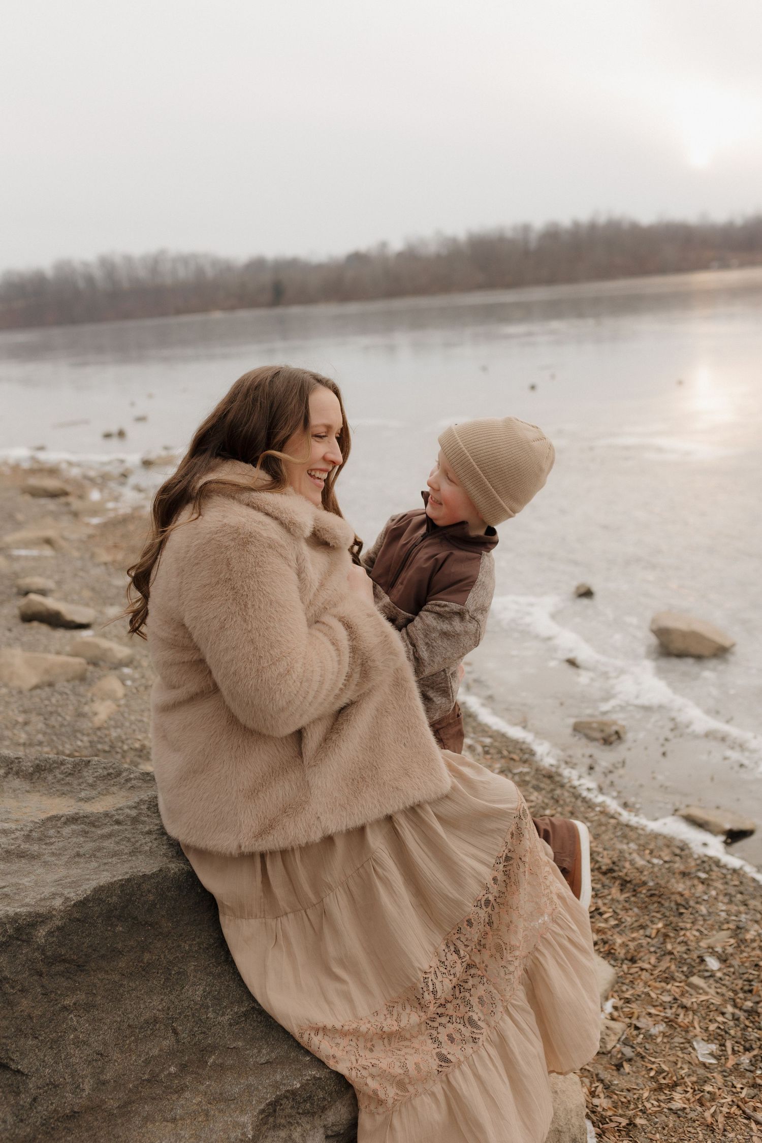 A tender moment shared between two people in cozy winter wear by a frozen lake.