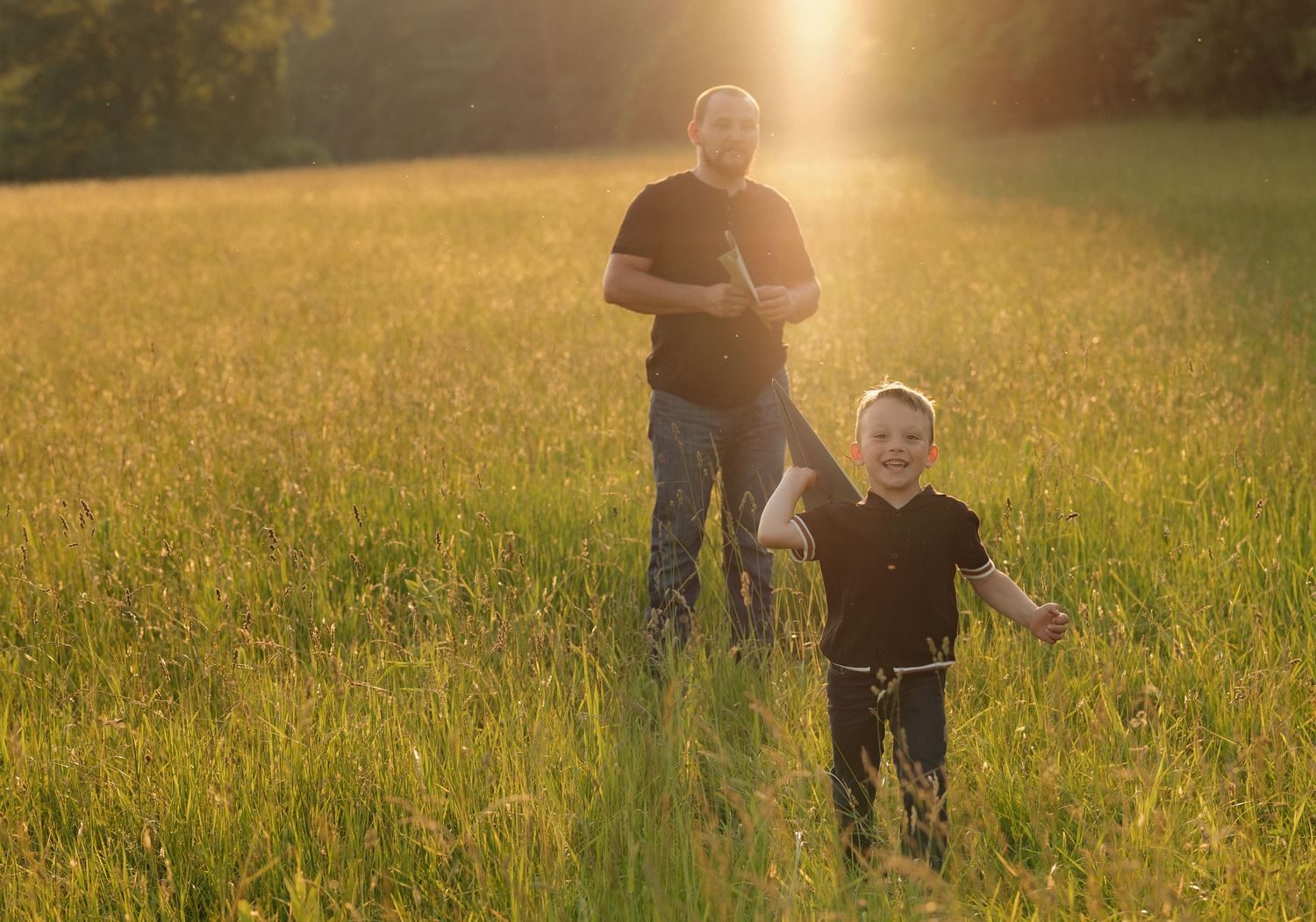 Family enjoying golden hour in a meadow with warm backlighting.