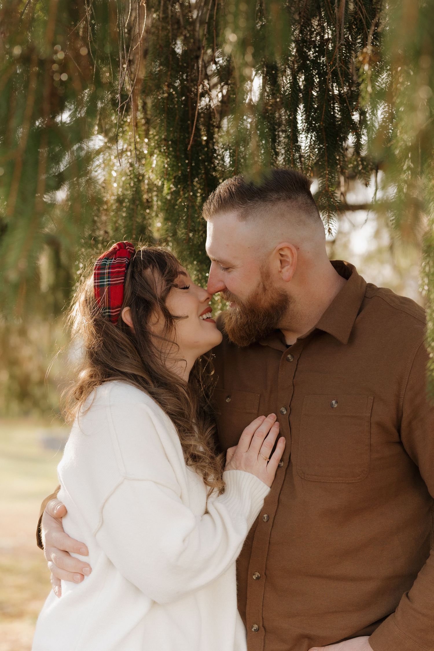 Romantic couple sharing an intimate moment under willow trees.