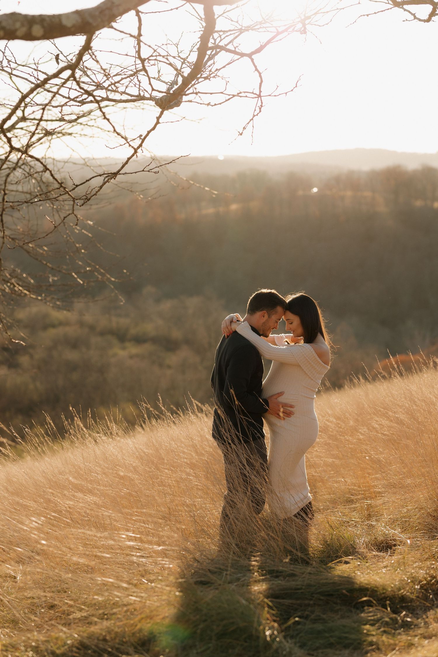A romantic couple sharing intimate moments in a sunlit field with tall grass.