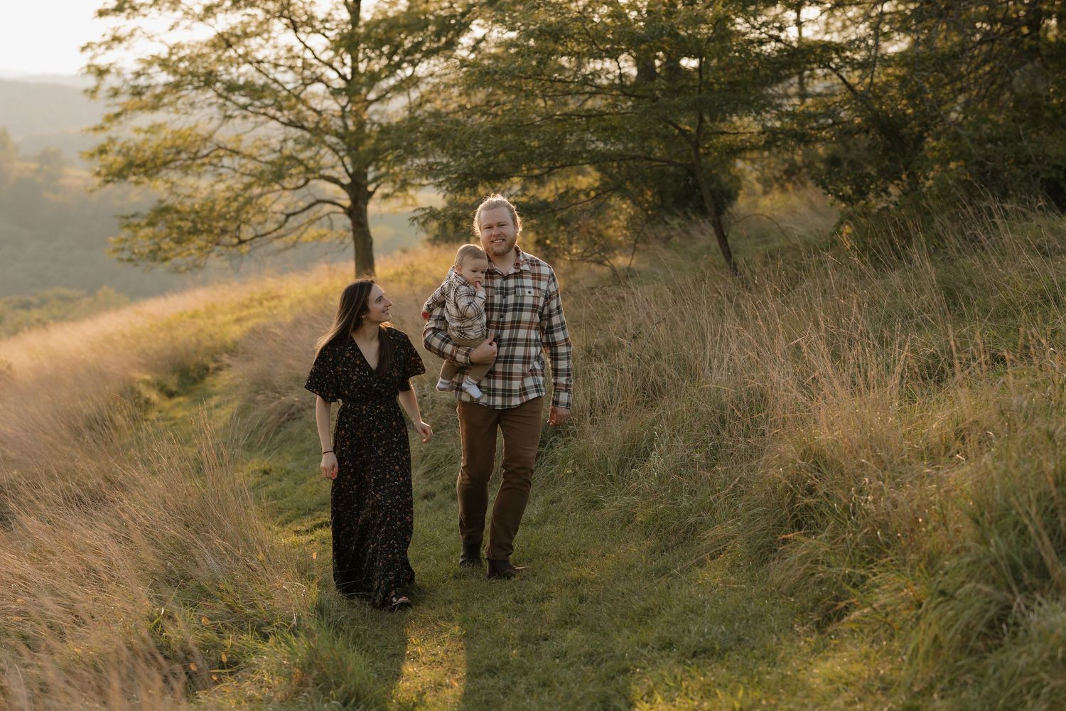Two people walking together on a scenic hillside trail at sunset.