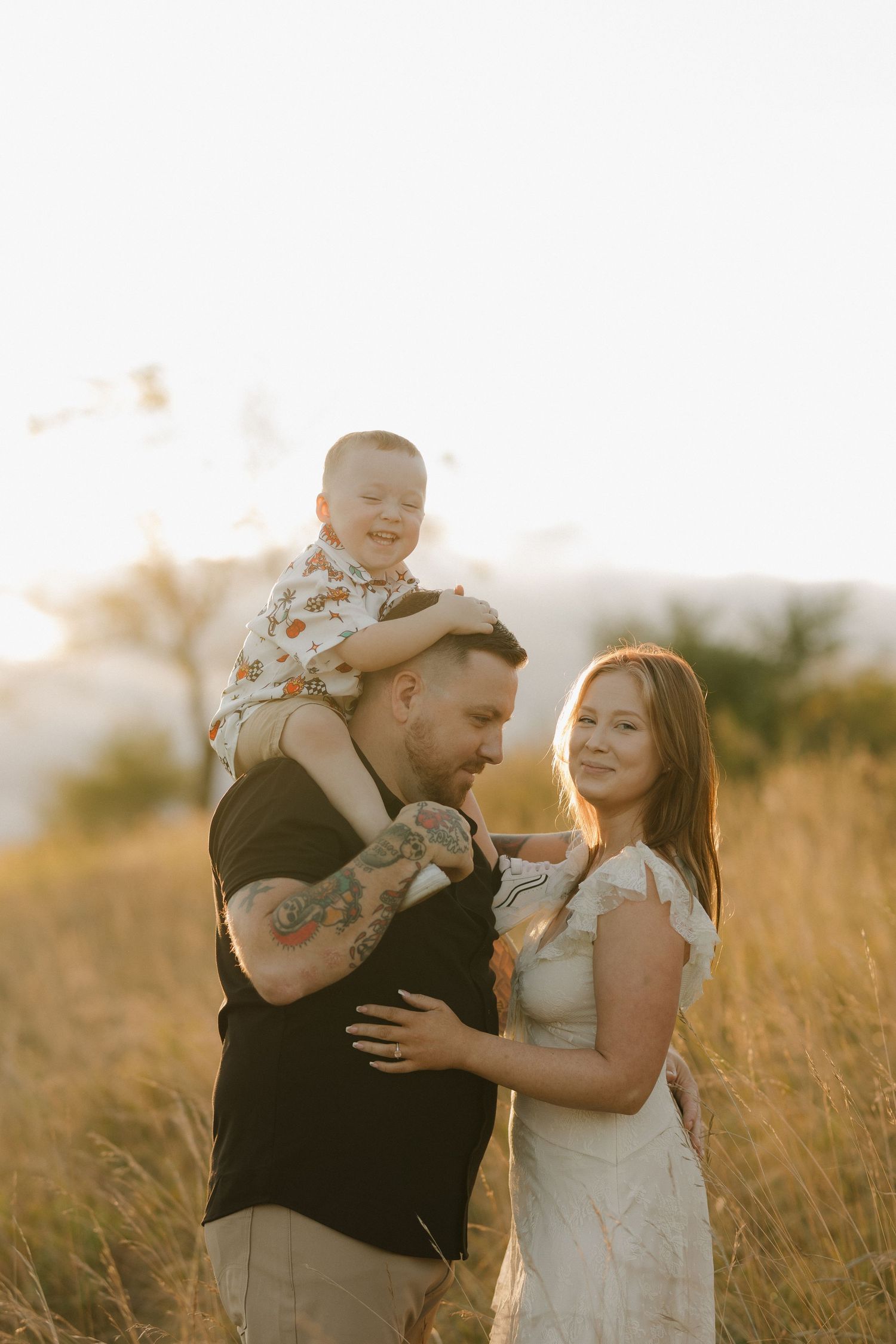 Family shares loving moments in a golden sunset field.