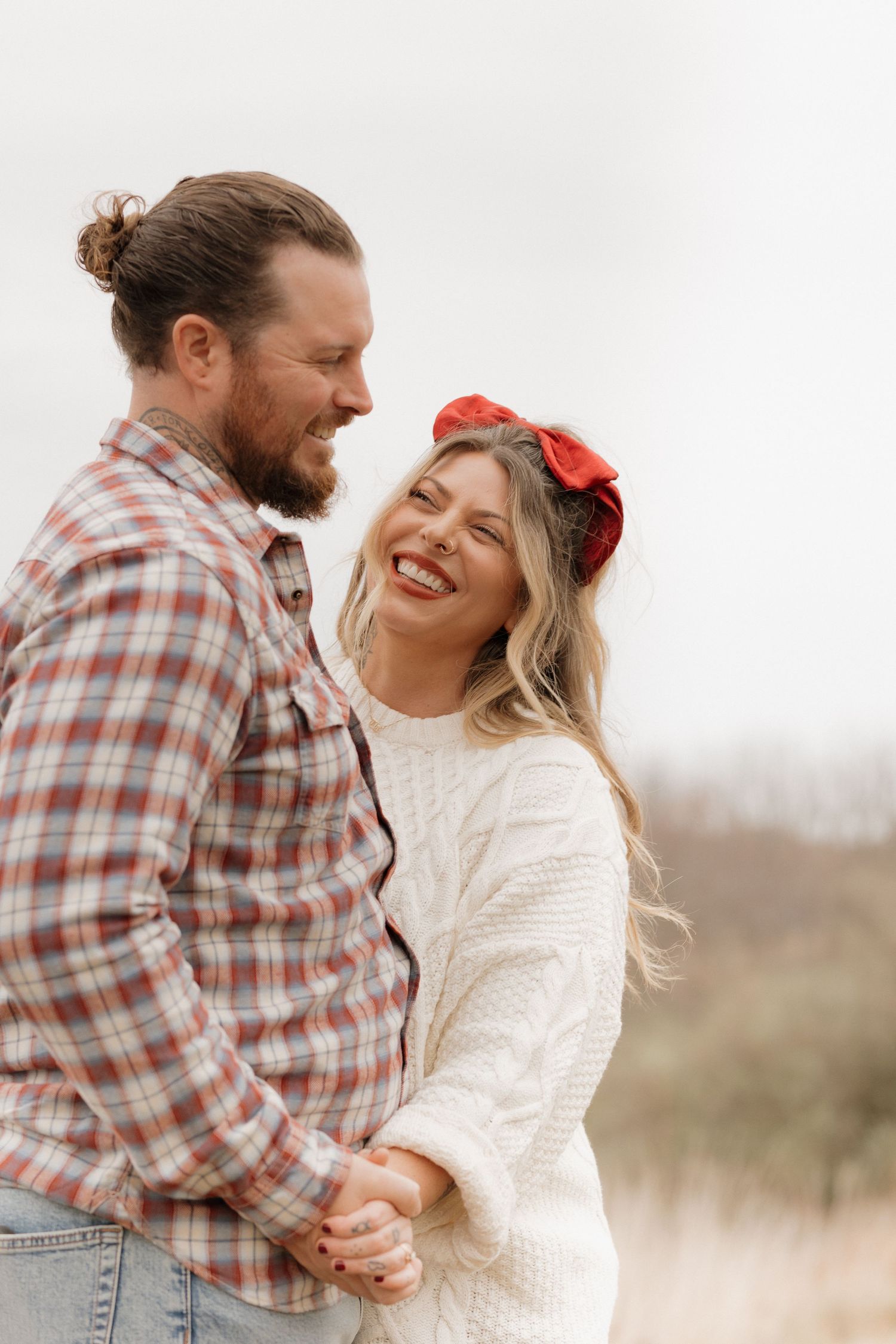 Couple sharing joyful laughter during casual outdoor portrait session.