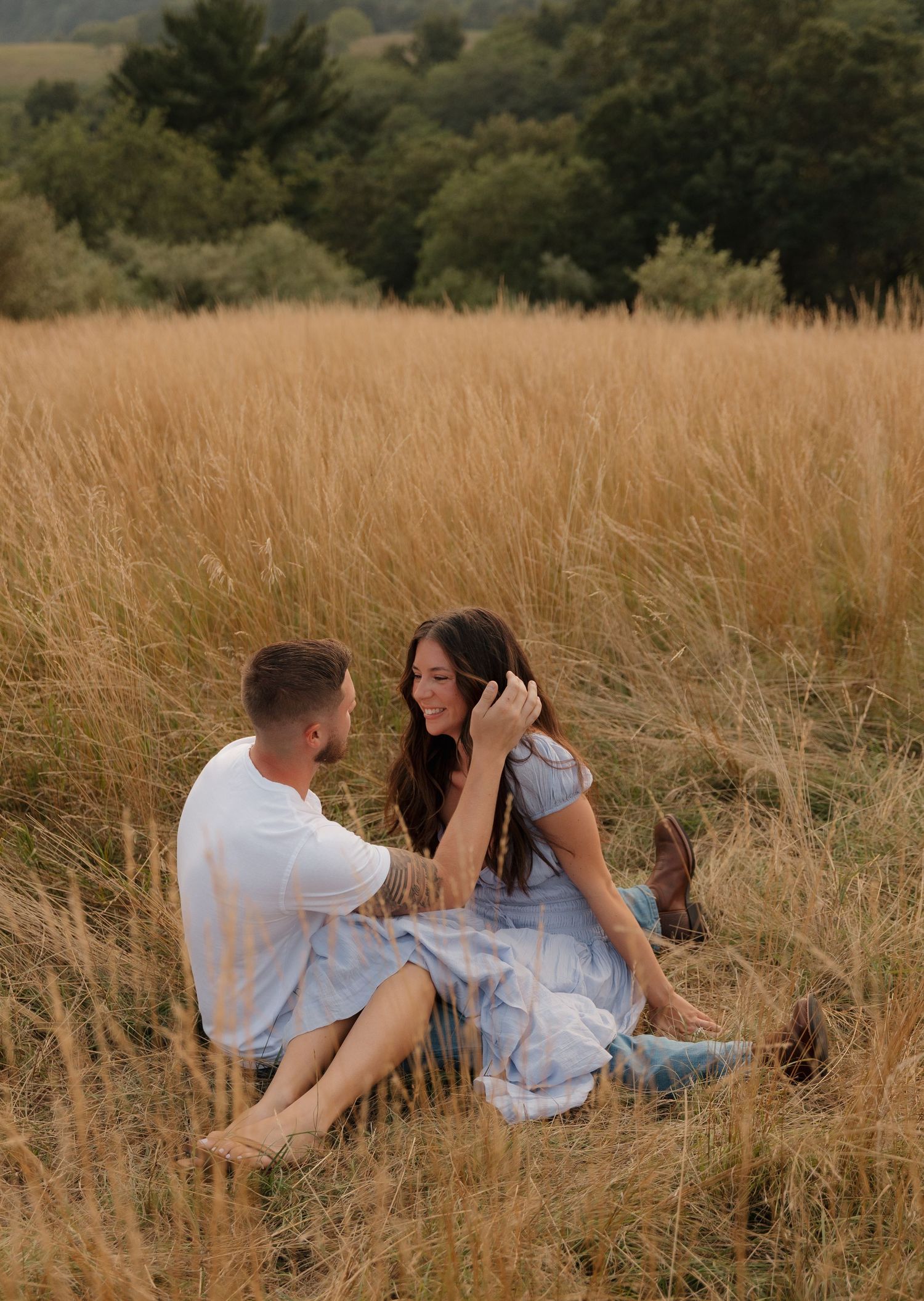 Playful couple relaxing in a golden meadow during an outdoor photo session.