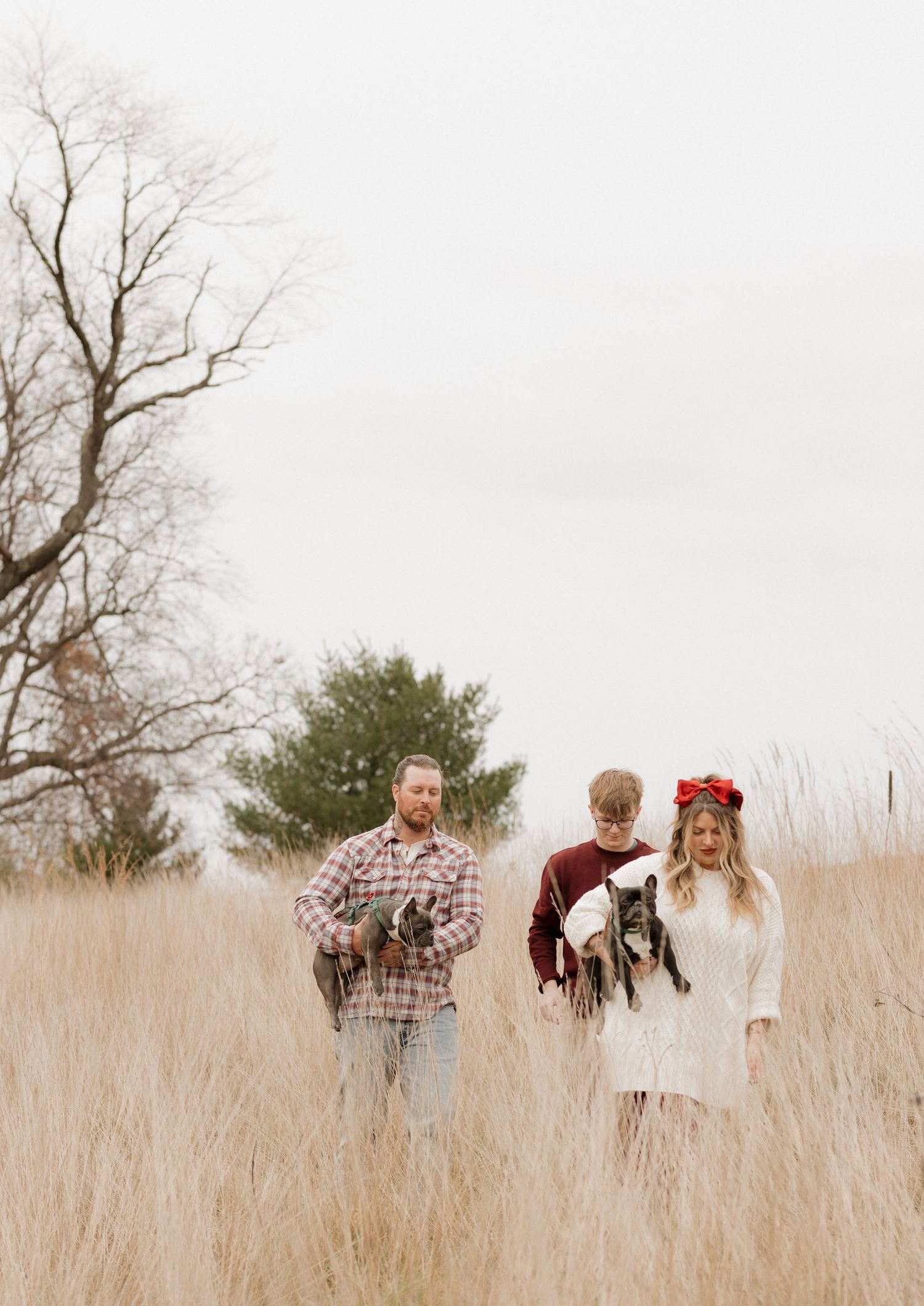 Family members walking through tall grass in a field at sunset.