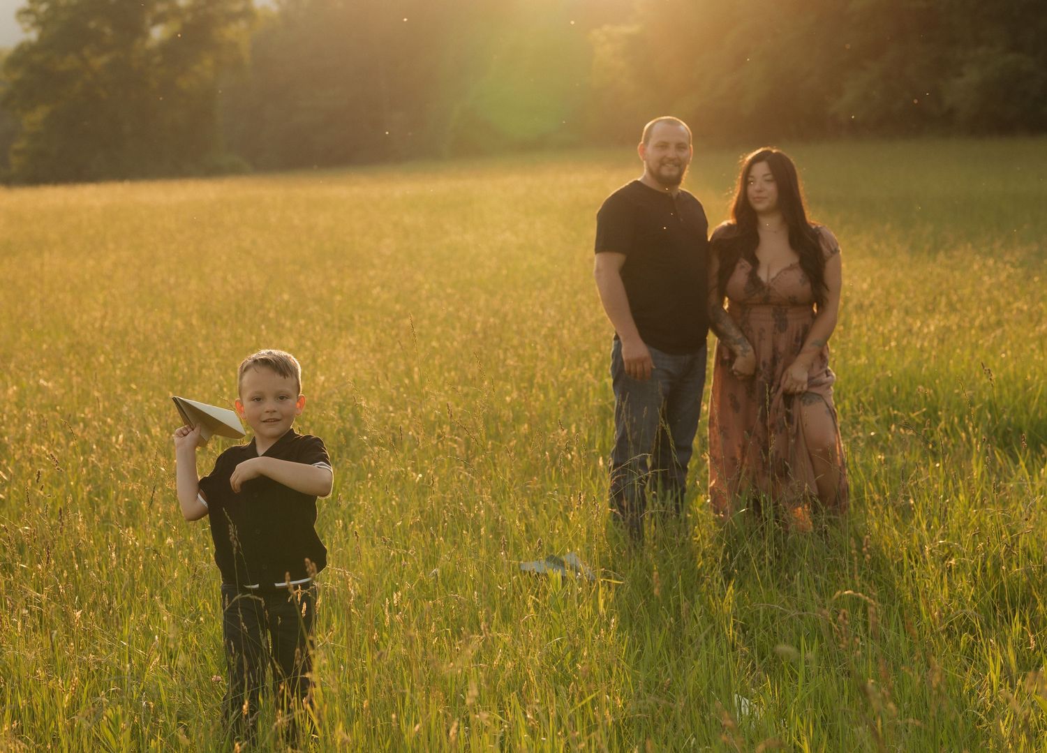 Family spending time together in sun-drenched field at dusk.