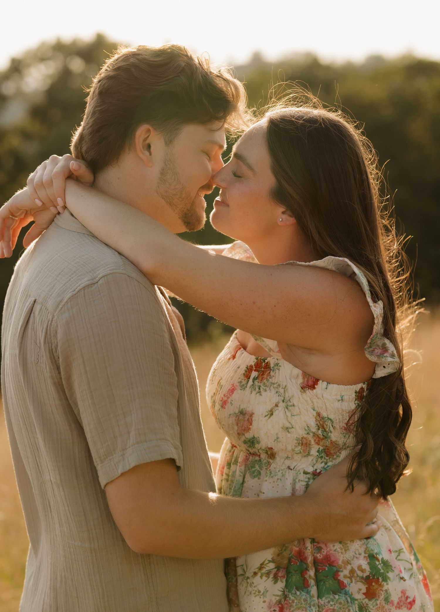 A romantic moment captured in a sunlit meadow with warm summer lighting.