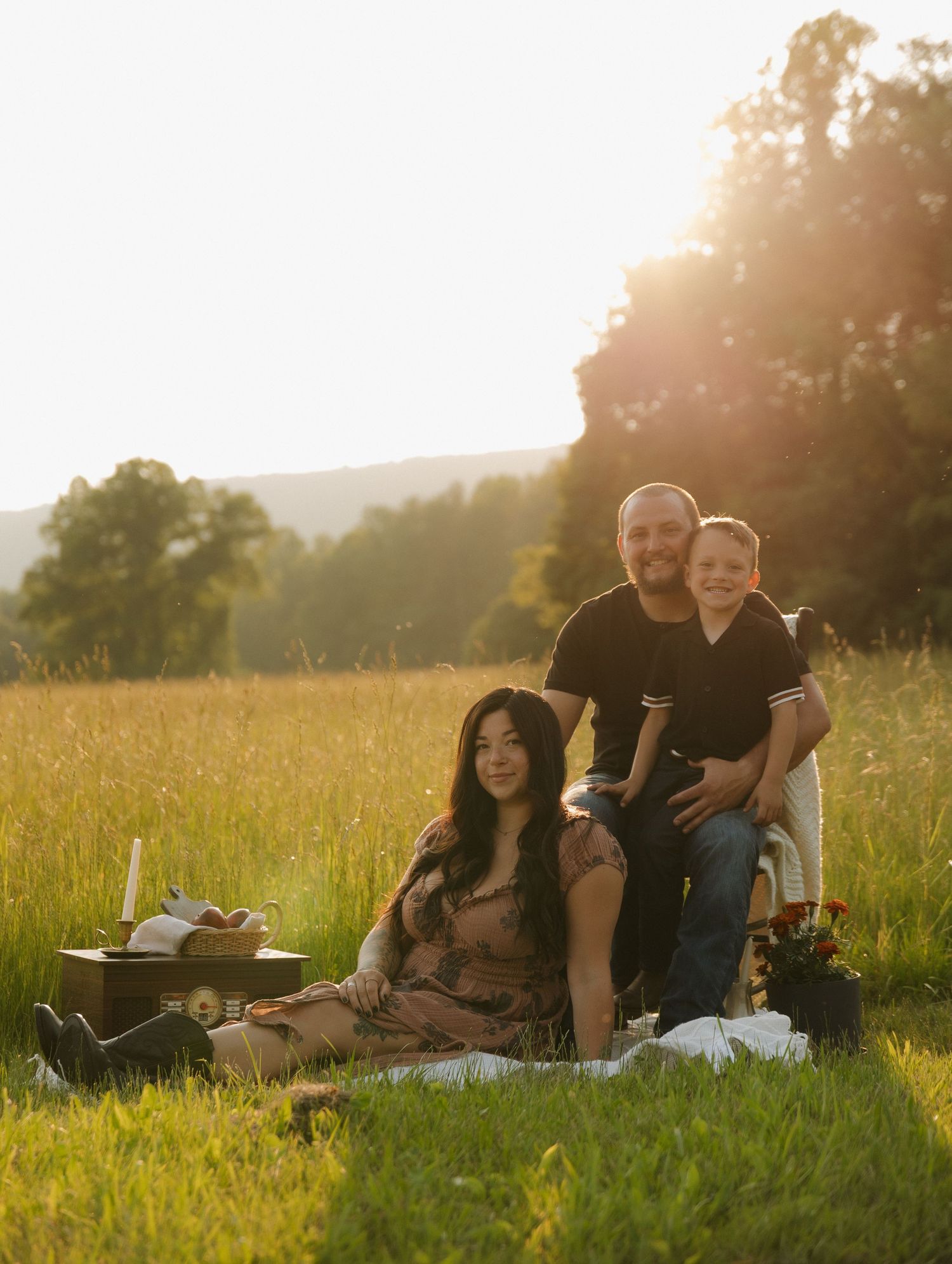 Group relaxing on blanket in grassy field during sunset.