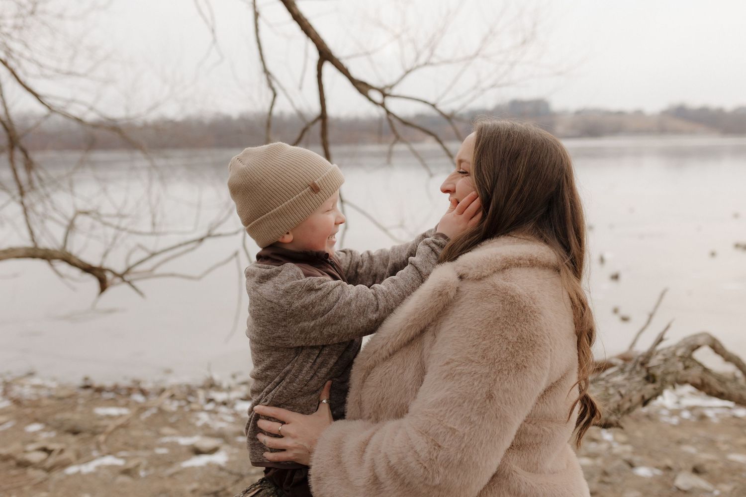Tender interaction between parent and child on a rocky beach during an overcast winter day.