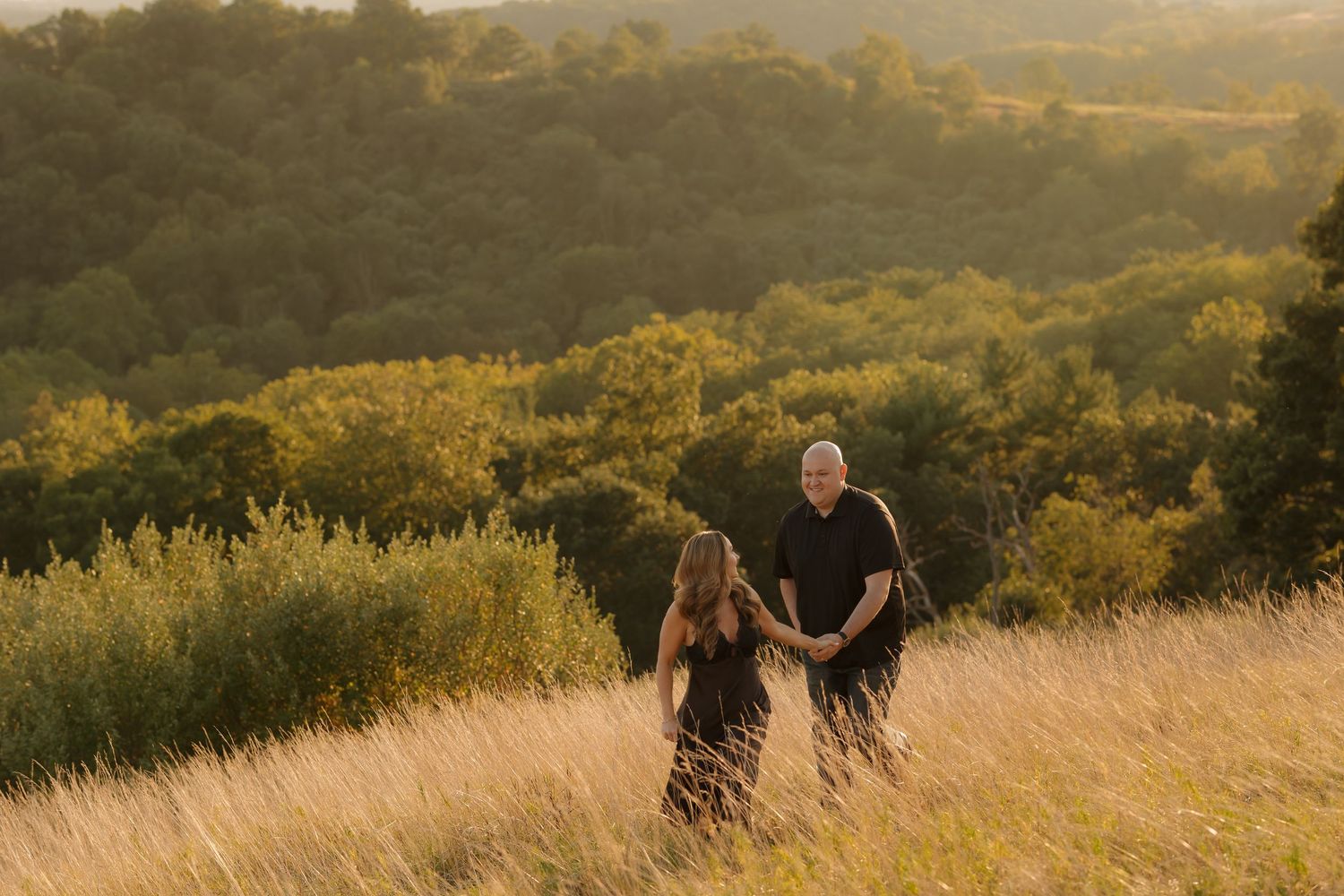 Golden sunset light illuminates a grassy hillside meadow with people enjoying a peaceful evening moment.