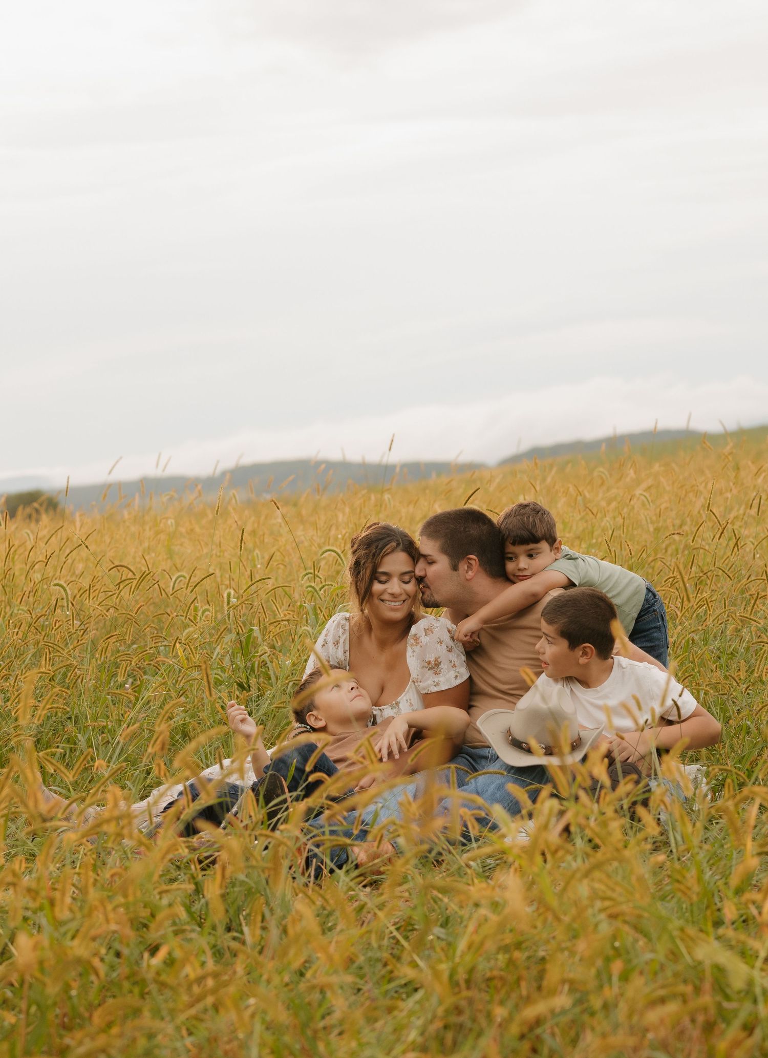 Happy family lying together in a golden wheat field during a playful photo session.