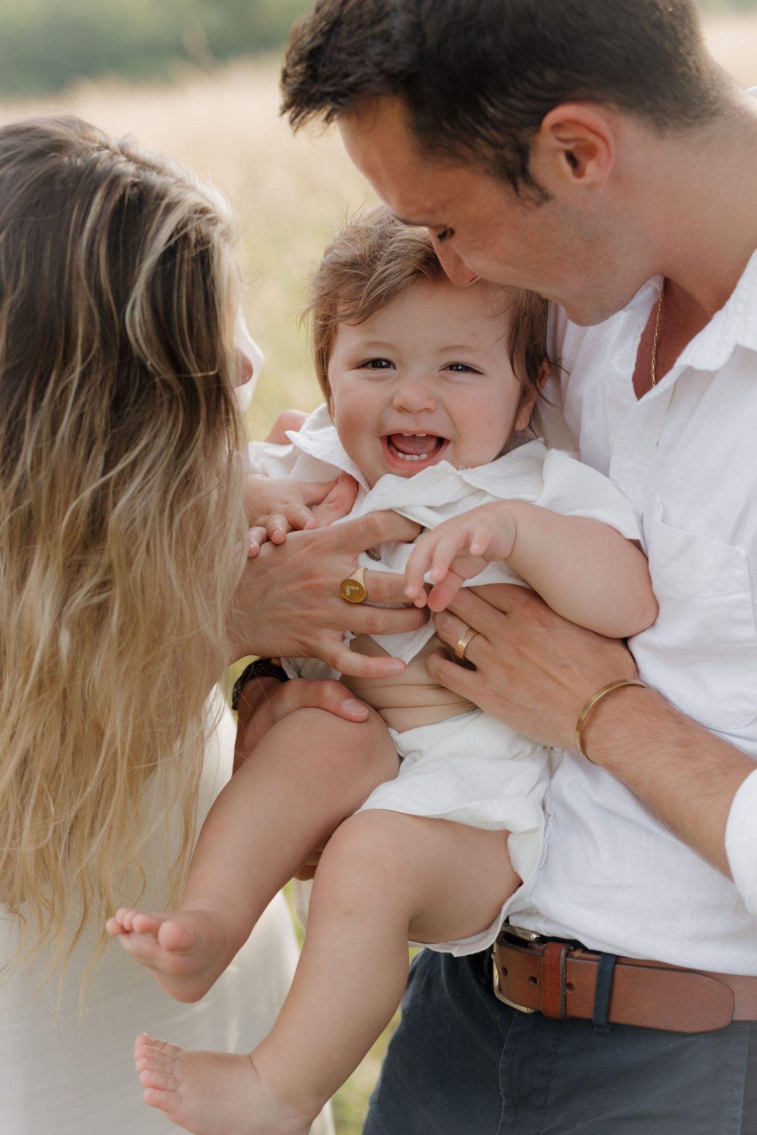 Family sharing playful moments together outdoors in white clothing.